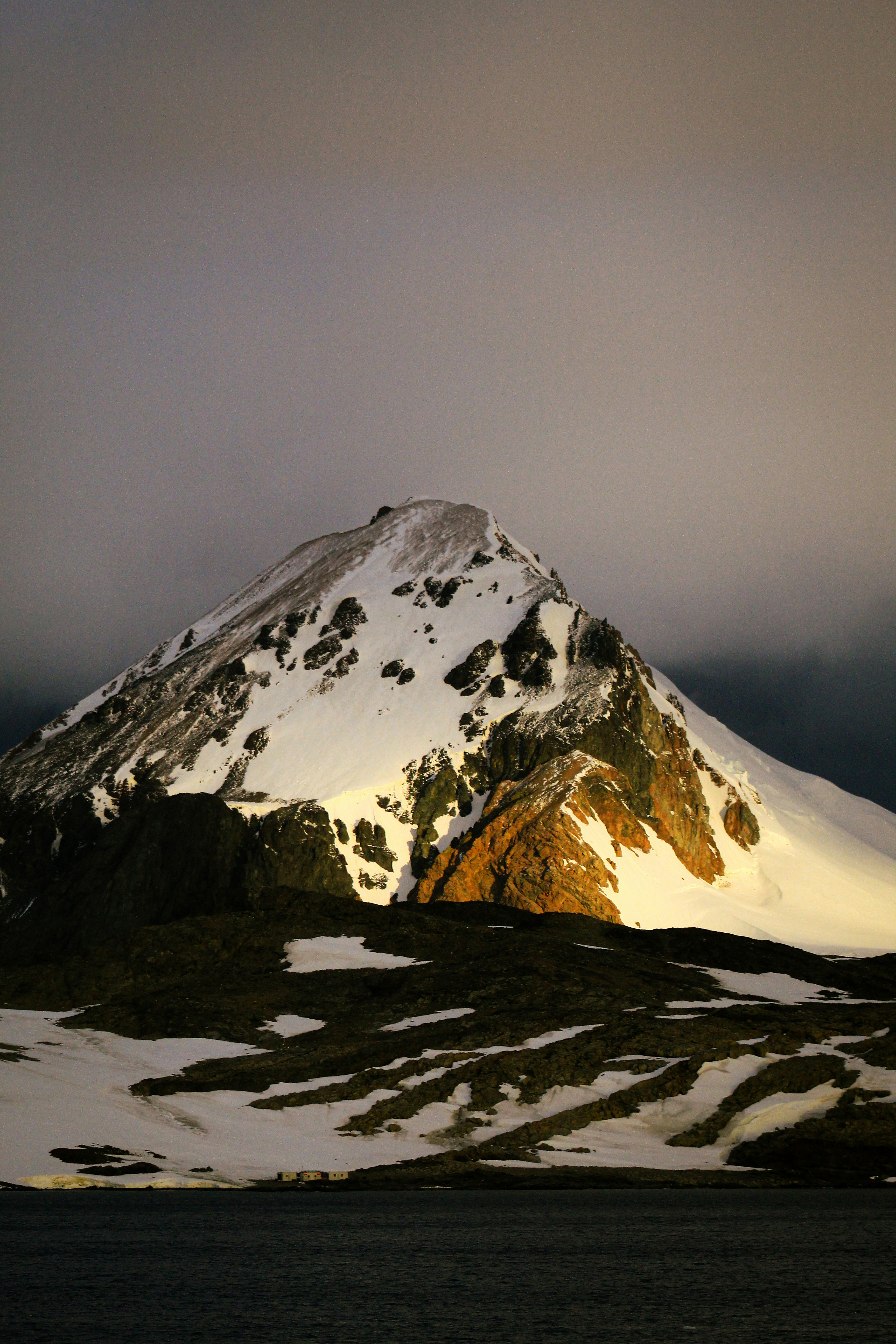 A mountain covered in snow under a cloudy sky