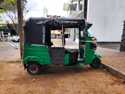 A green three wheeled vehicle parked on the side of the road