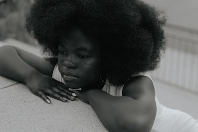 A woman with an afro leaning on a wall