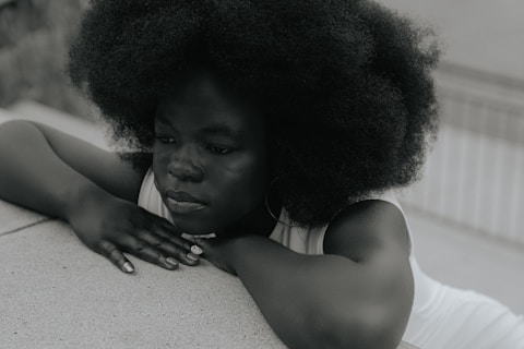 A woman with an afro leaning on a wall