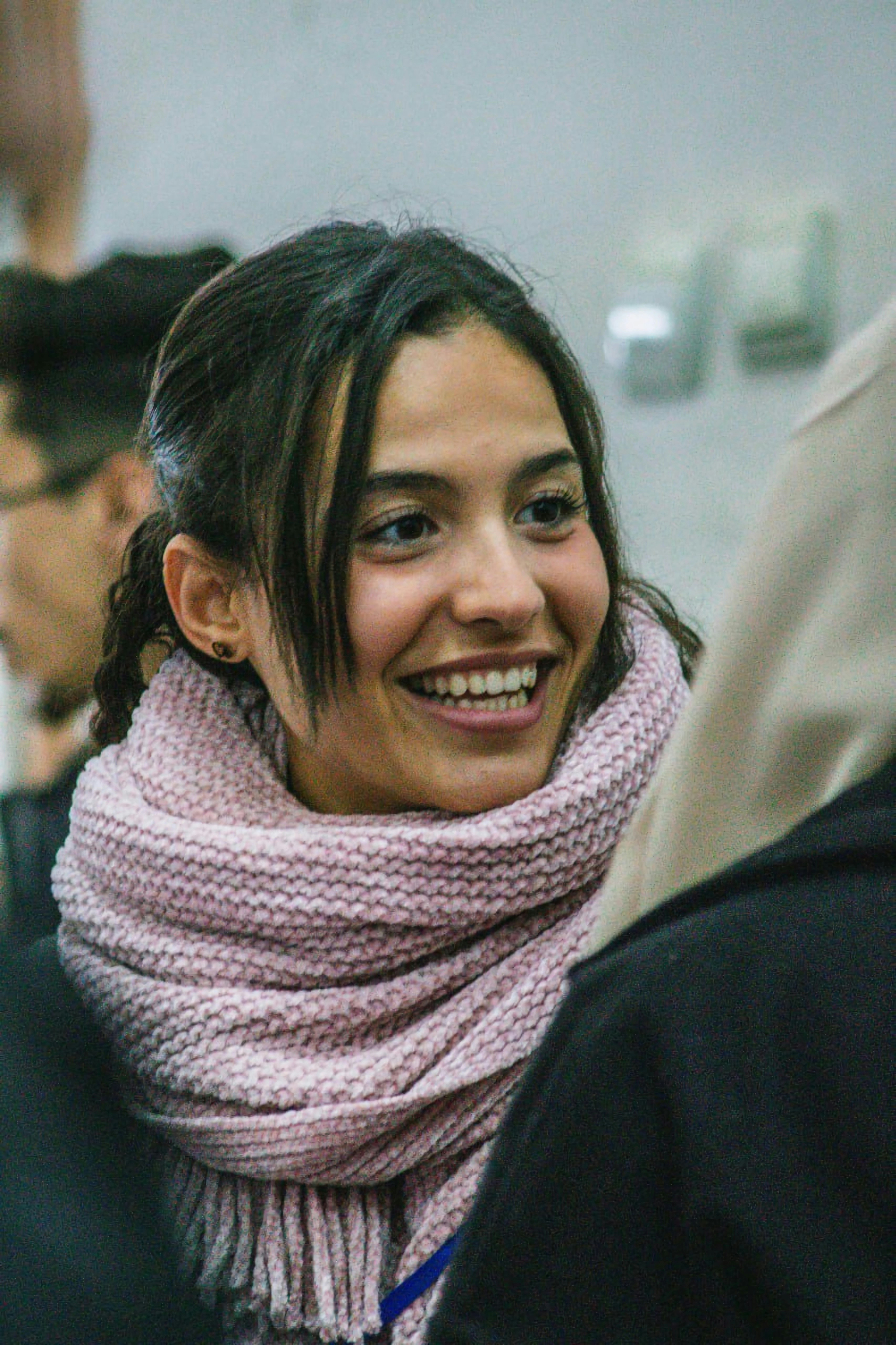 A smiling woman wearing a pink scarf around her neck