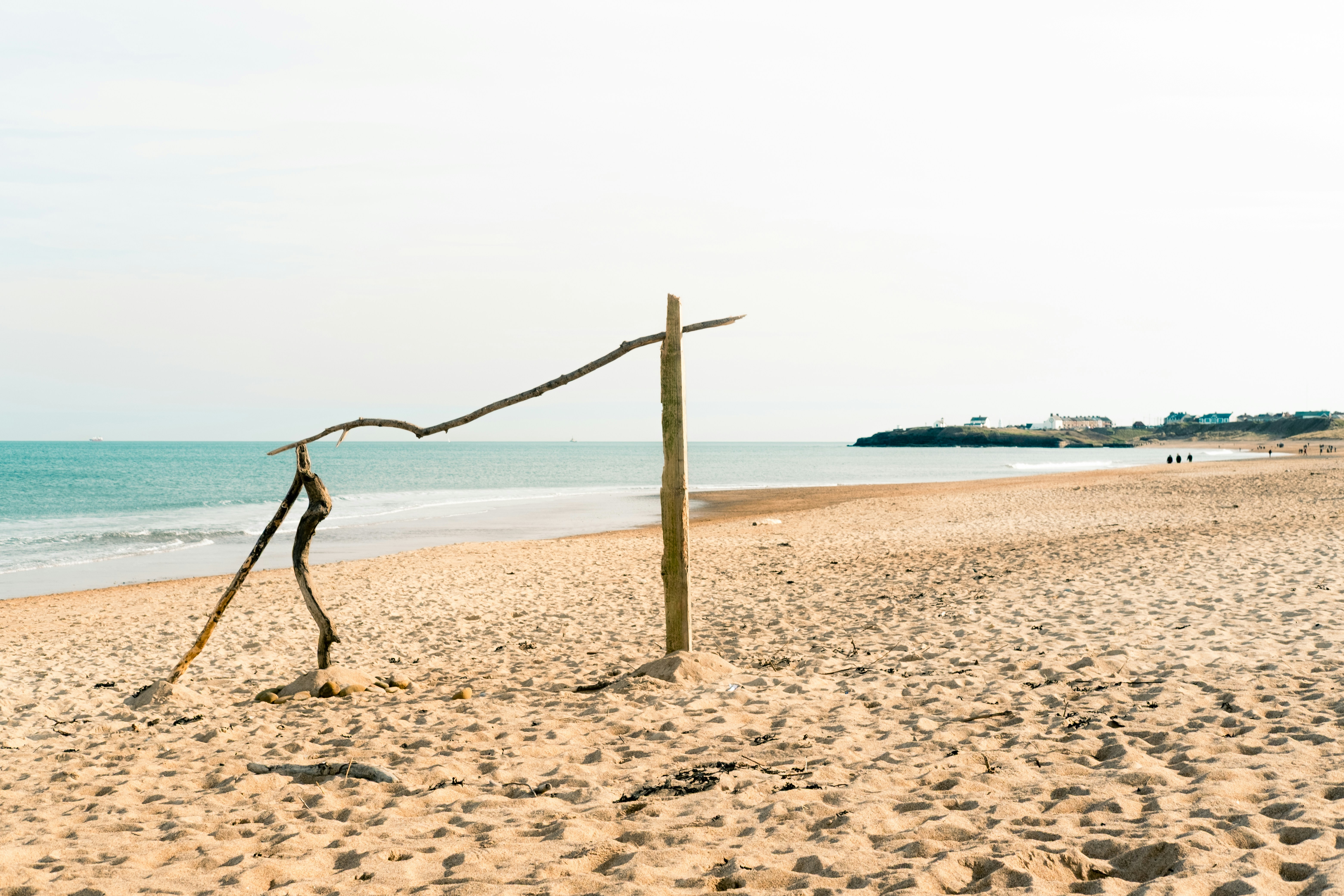 A beach with a pole and a boat in the water