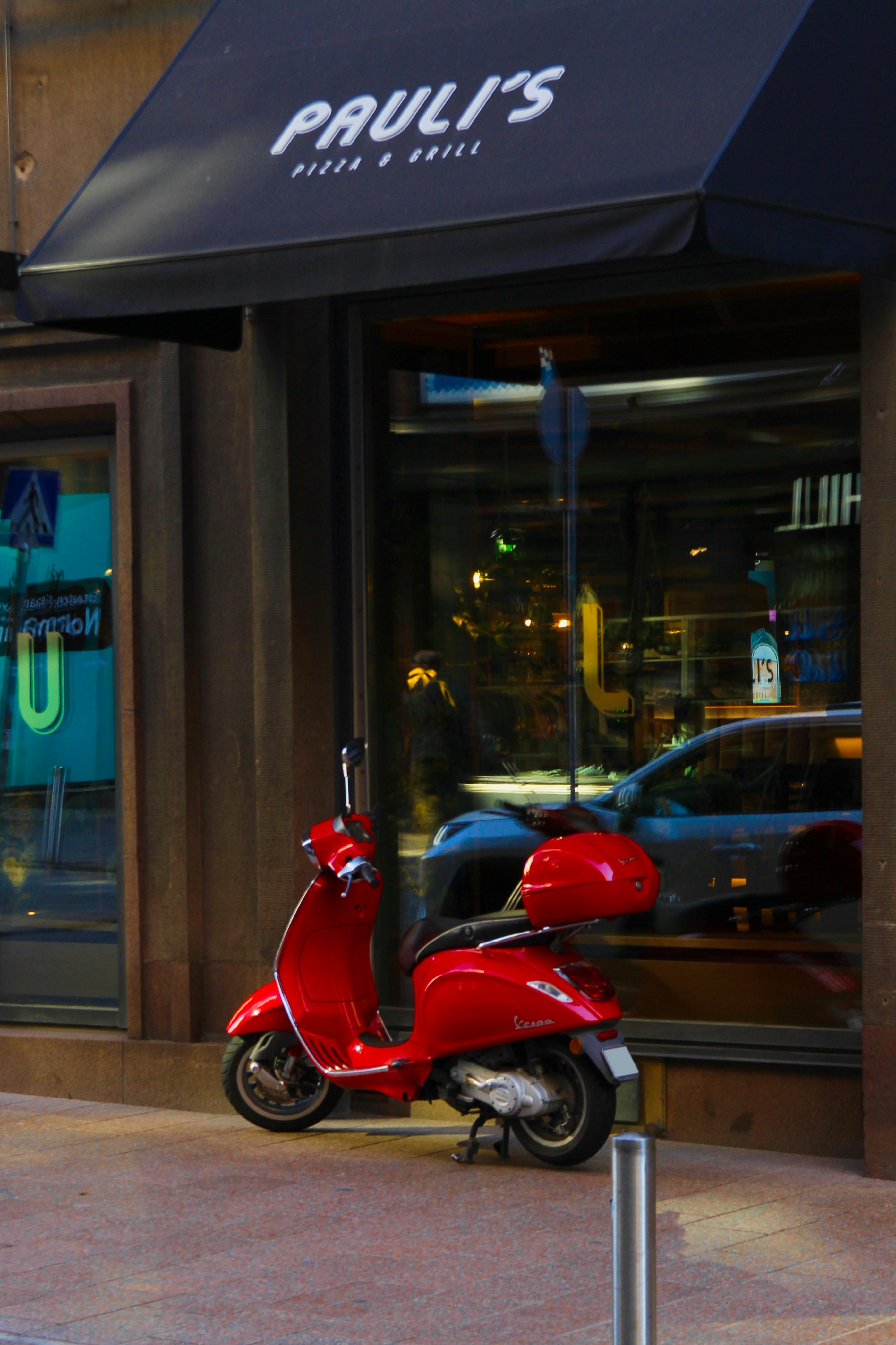 A red scooter parked in front of a restaurant