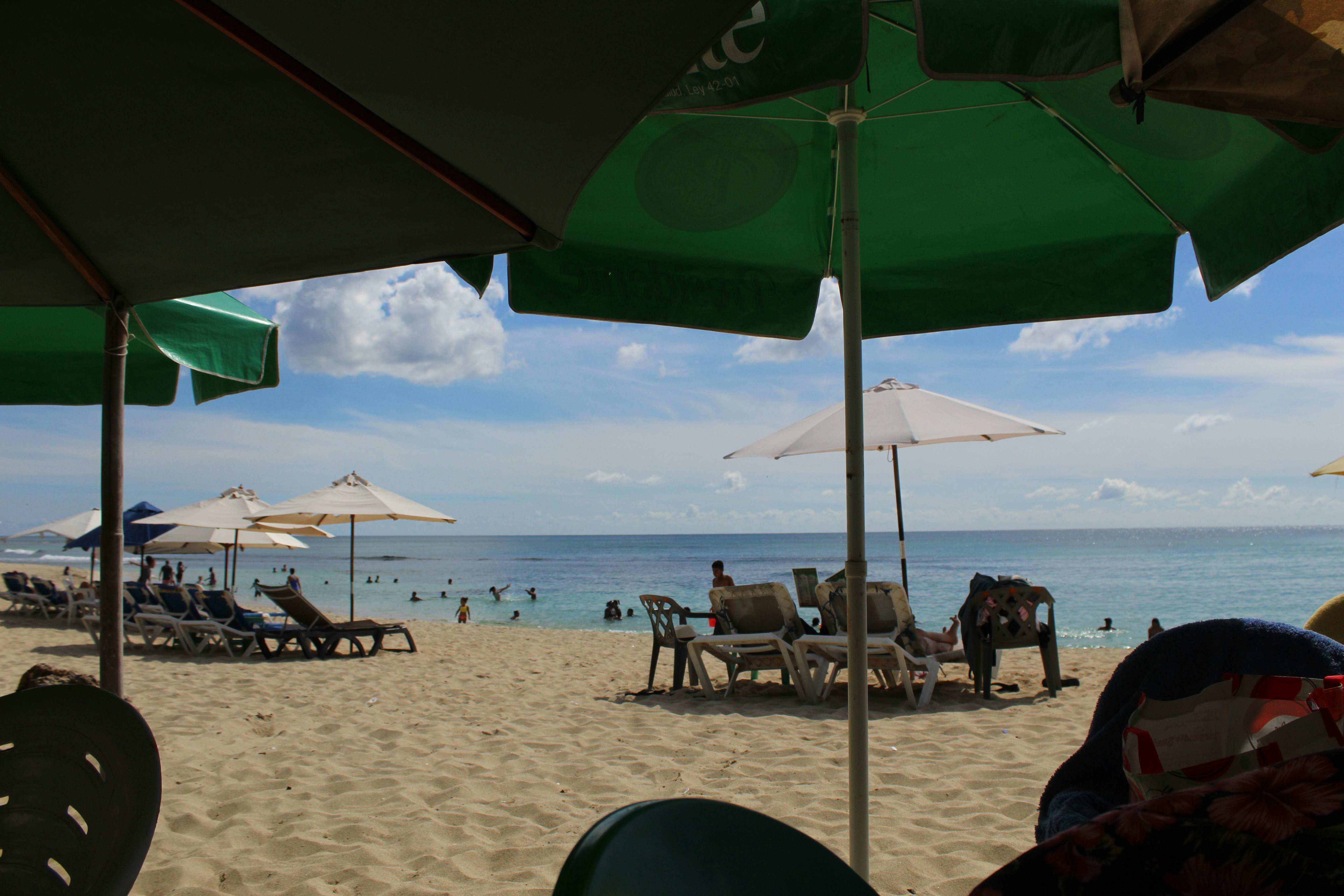A group of people sitting under umbrellas on a beach