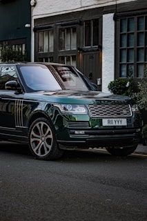 A green range rover parked on the side of the road