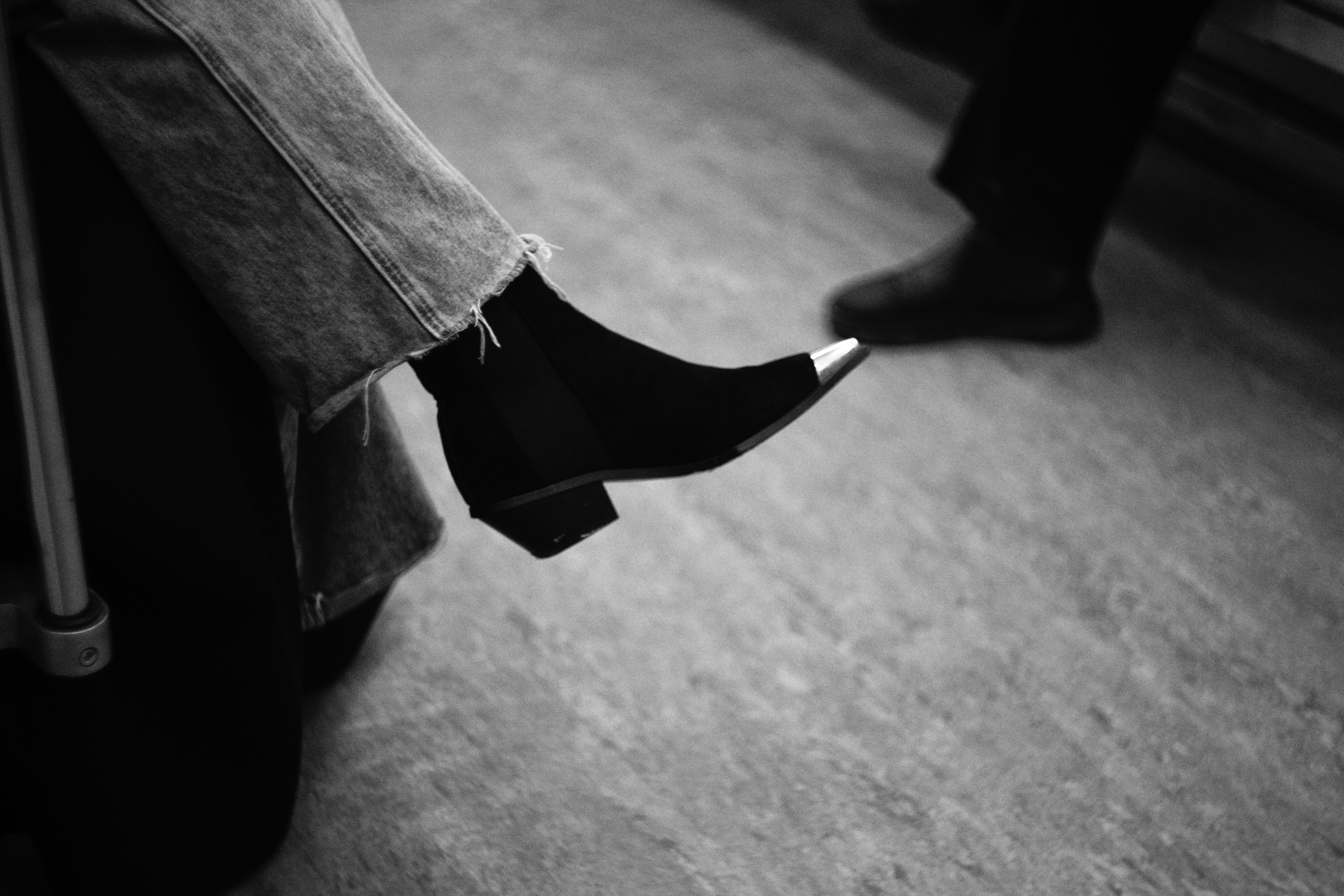 A black and white photo of a person's legs and shoes
