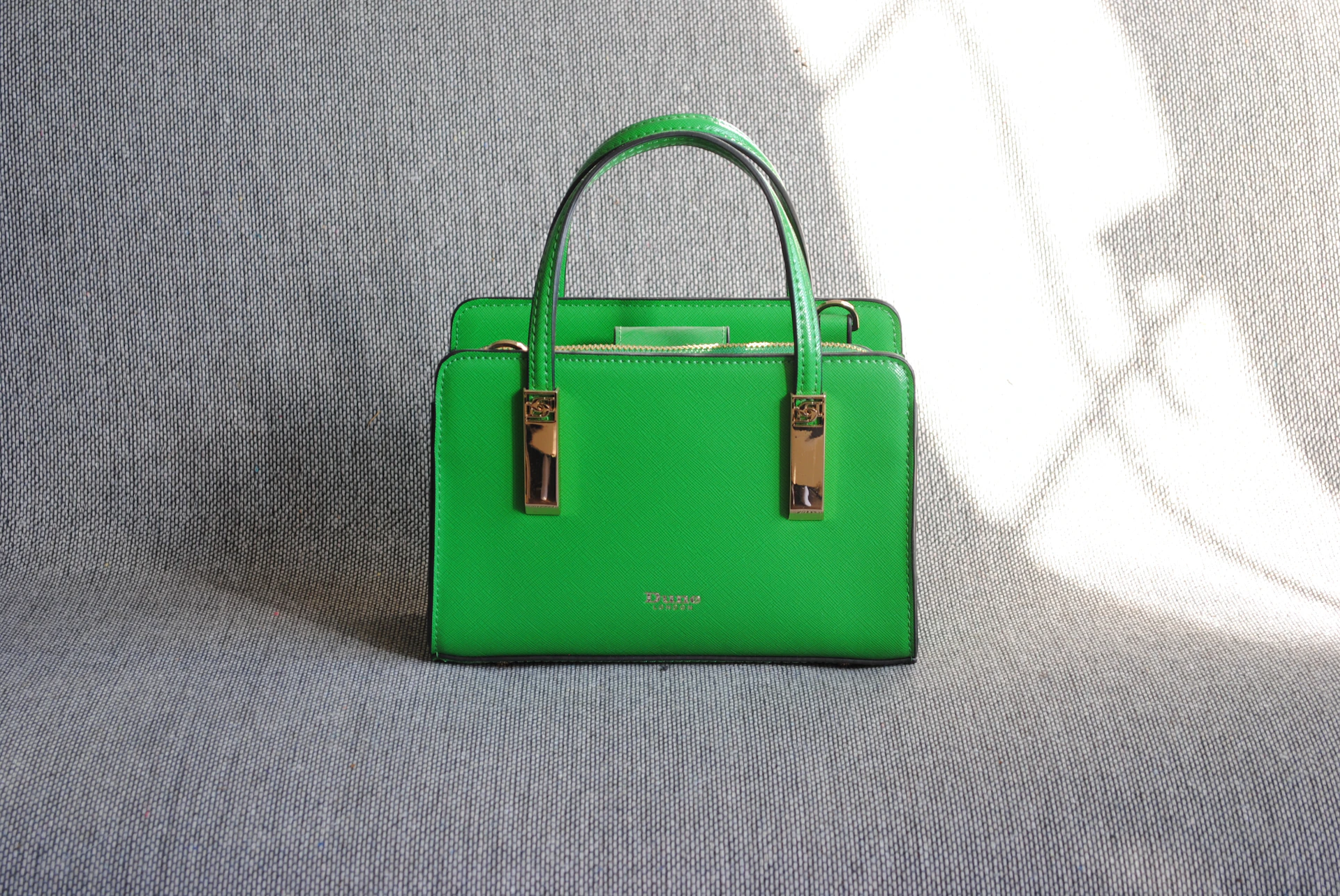 A bright green handbag sits on a gray surface
