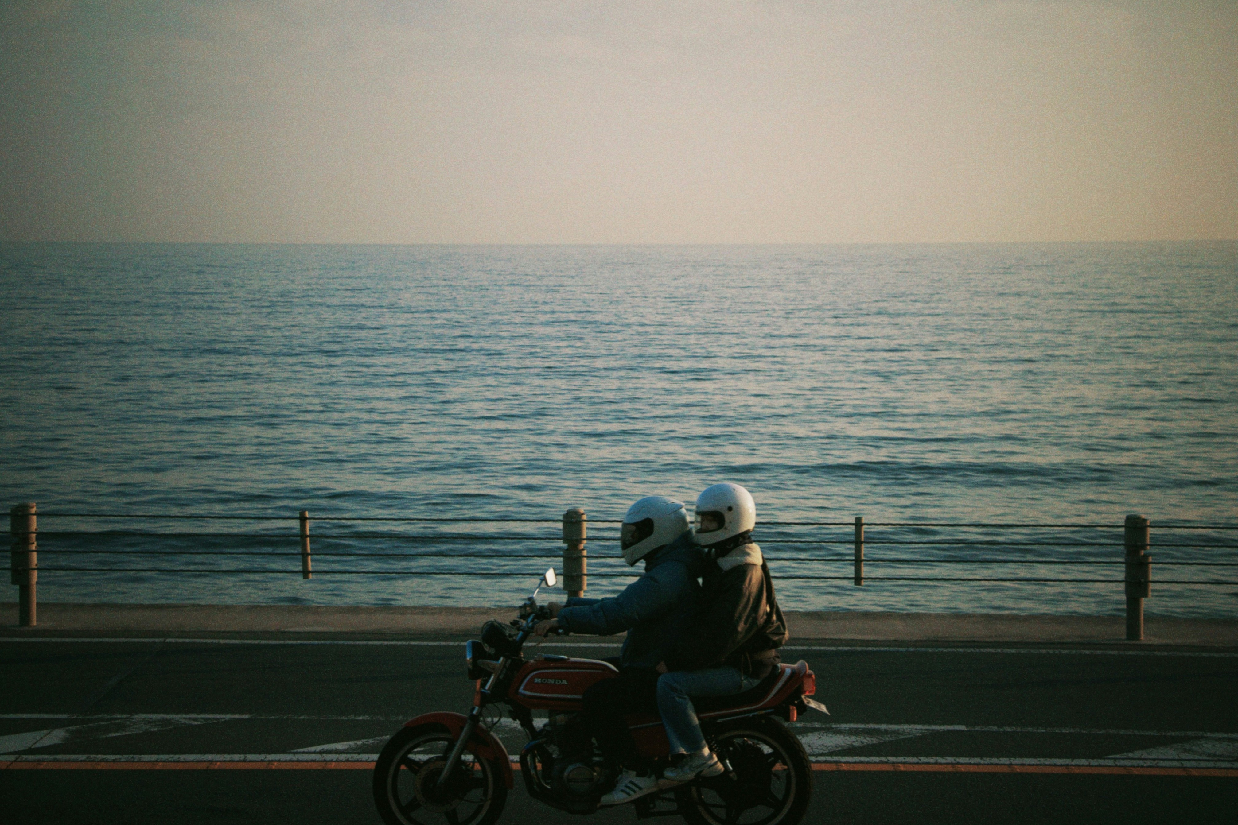 Couple rides a motorcycle by the sea.