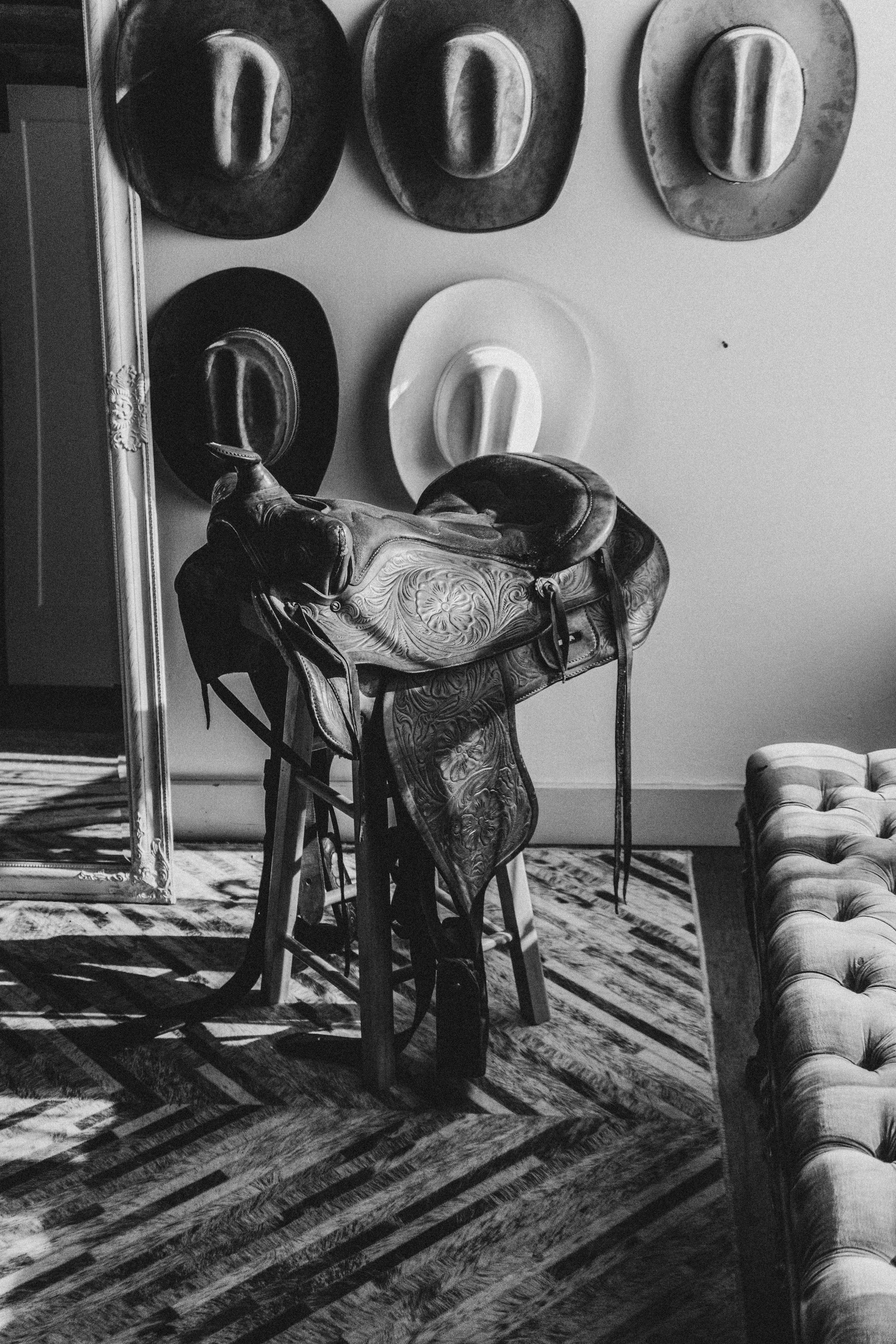 Cowboy hats and saddle on display in a room.