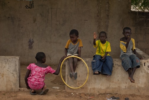 Children play together outdoors with a hoop.