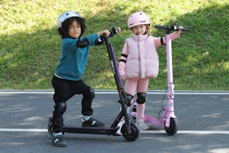 Two children are posing with their scooters.