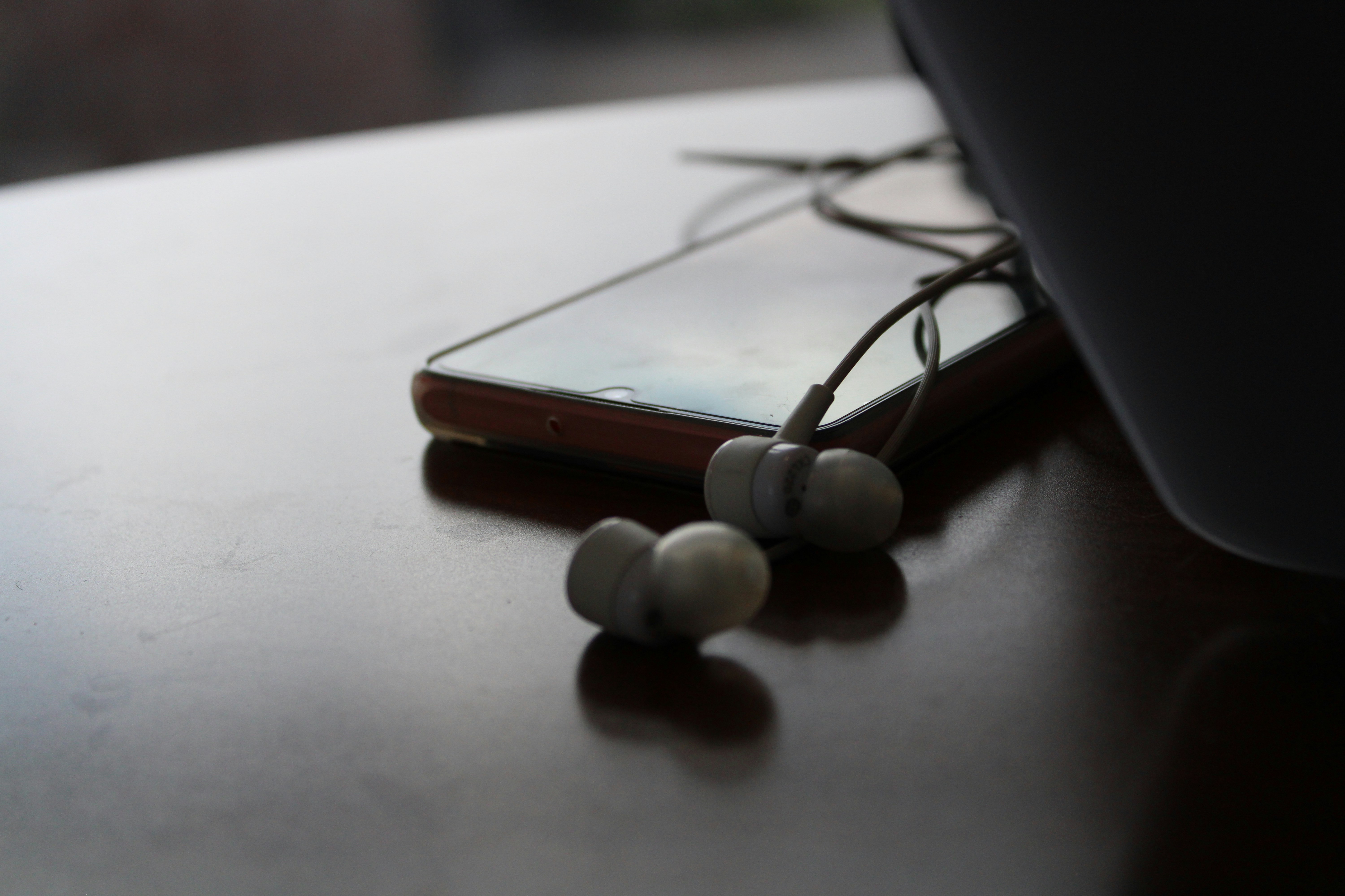 Phone and earbuds rest on a reflective surface.