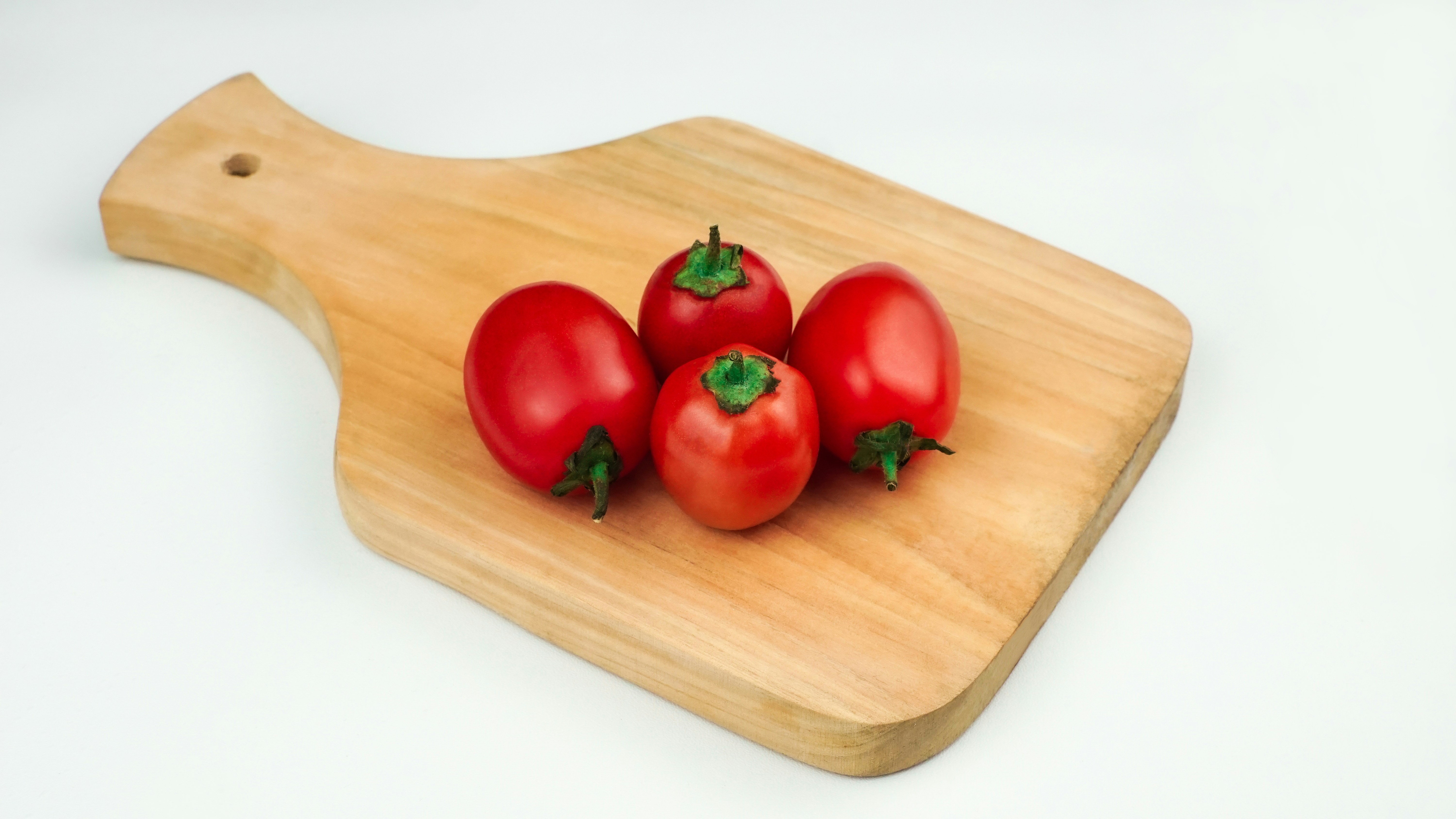 나무 도마에 빨간 토마토 4개.