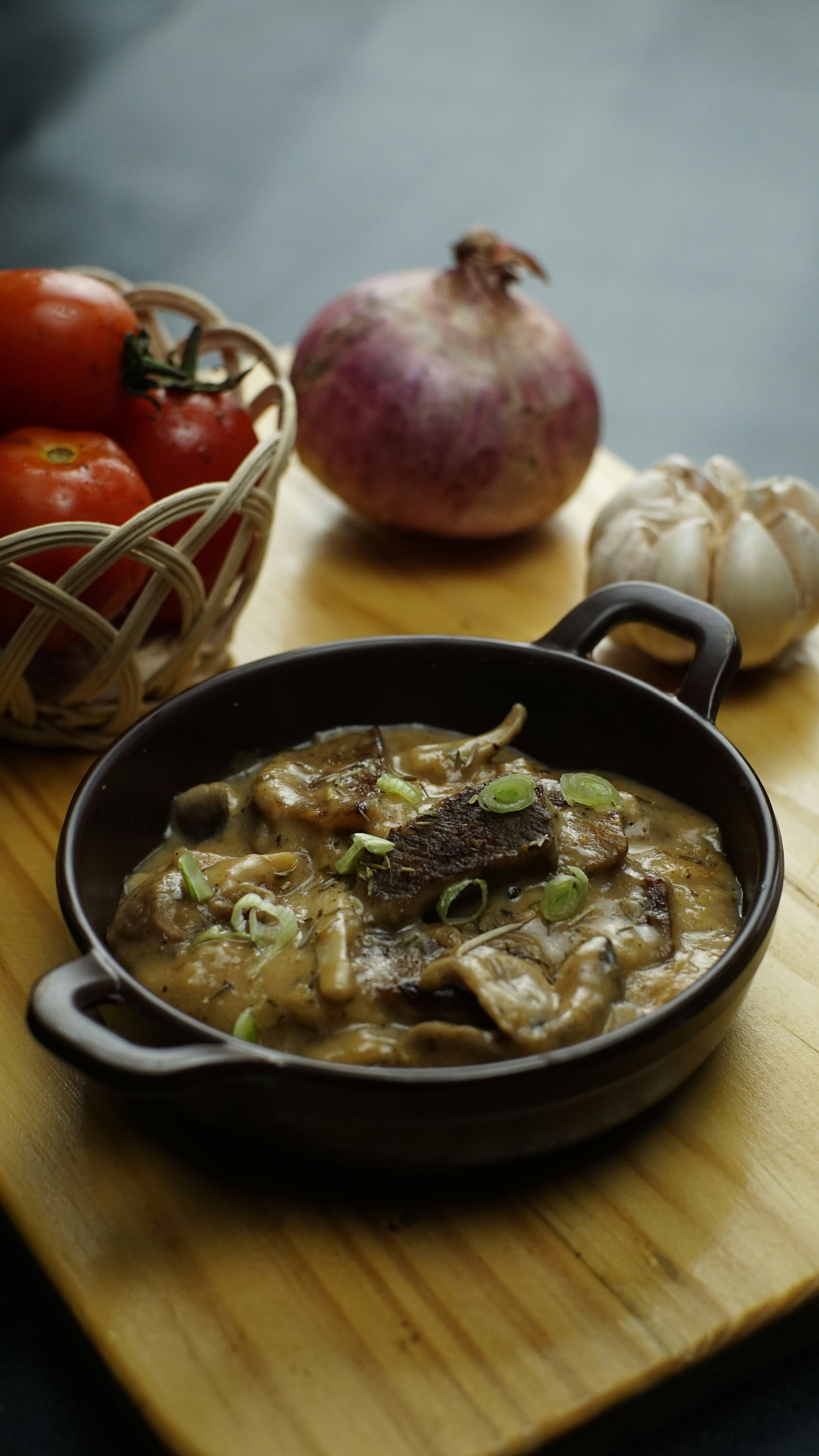 Beef stew and fresh ingredients on a wooden board.