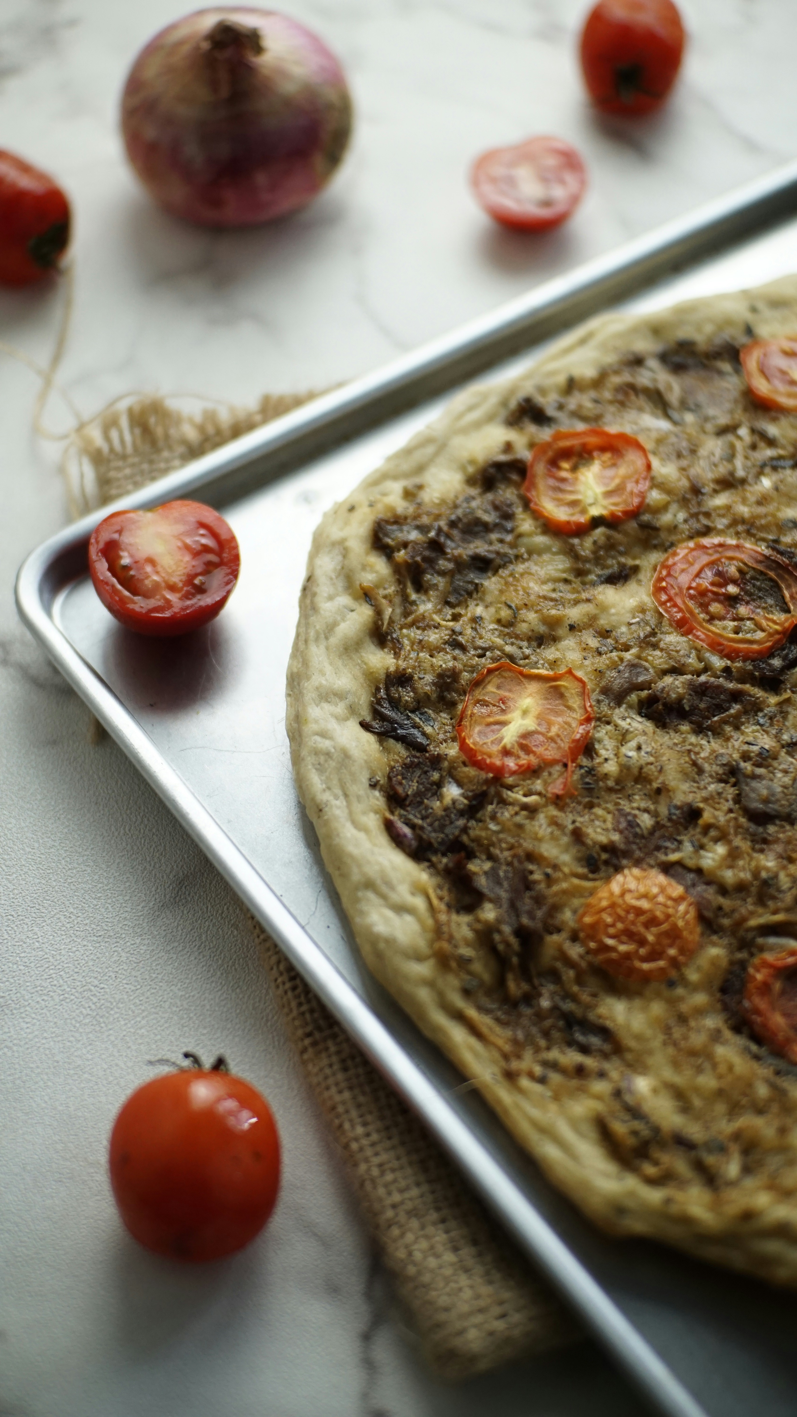 Una deliziosa pizza con pomodoro e cipolla su una teglia.