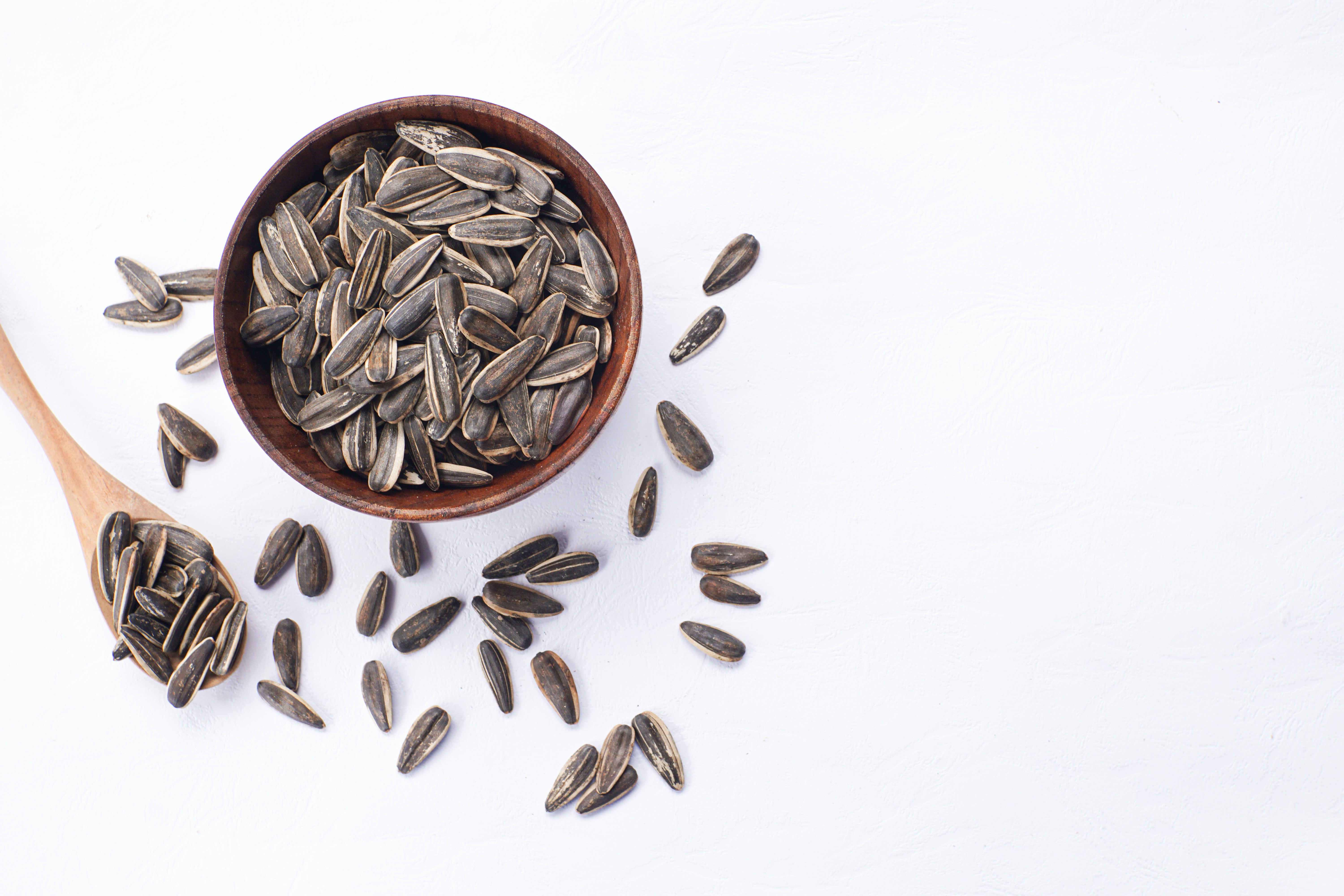 Sunflower seeds in a wooden bowl and spoon.