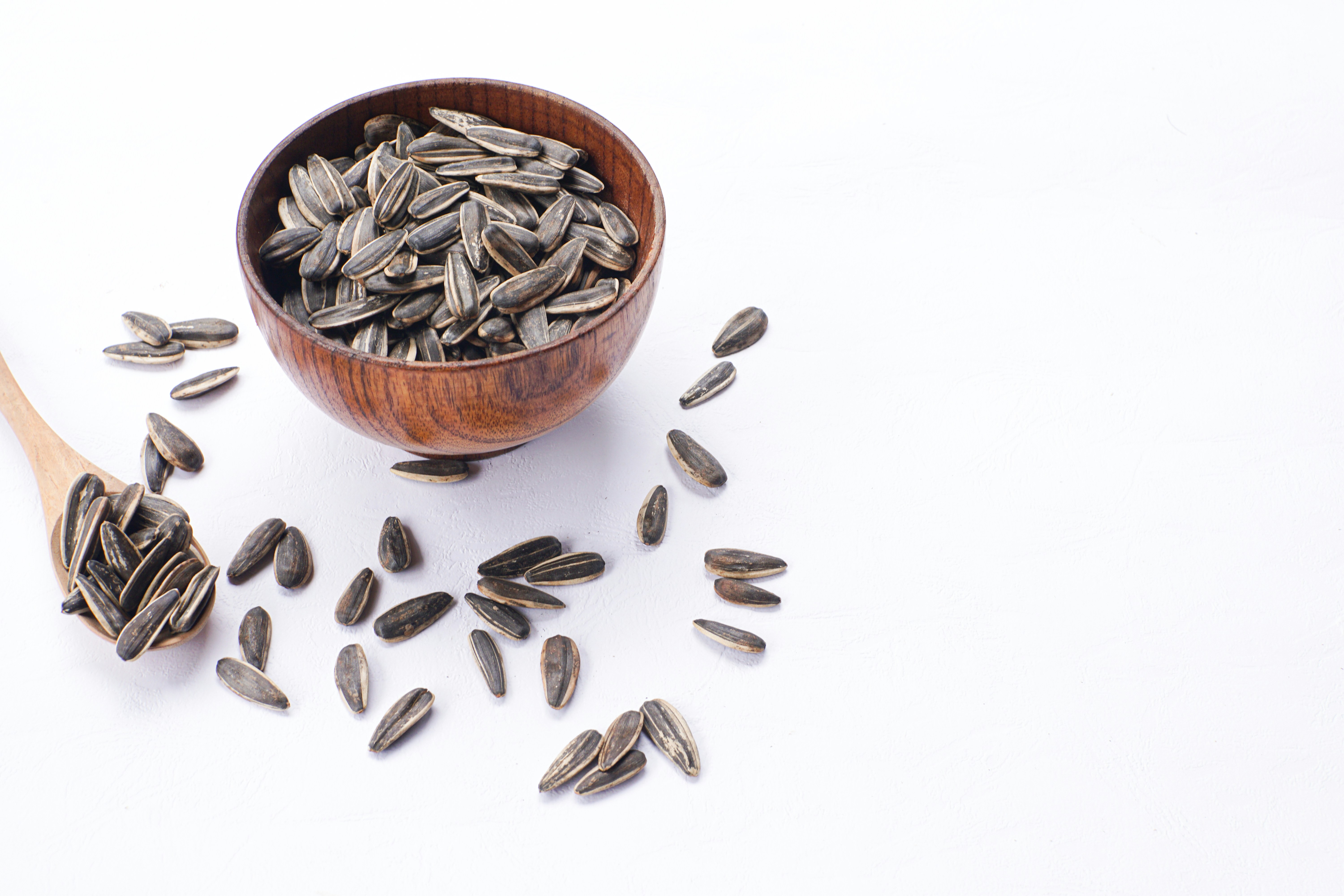 Sunflower seeds in a wooden bowl and spoon.