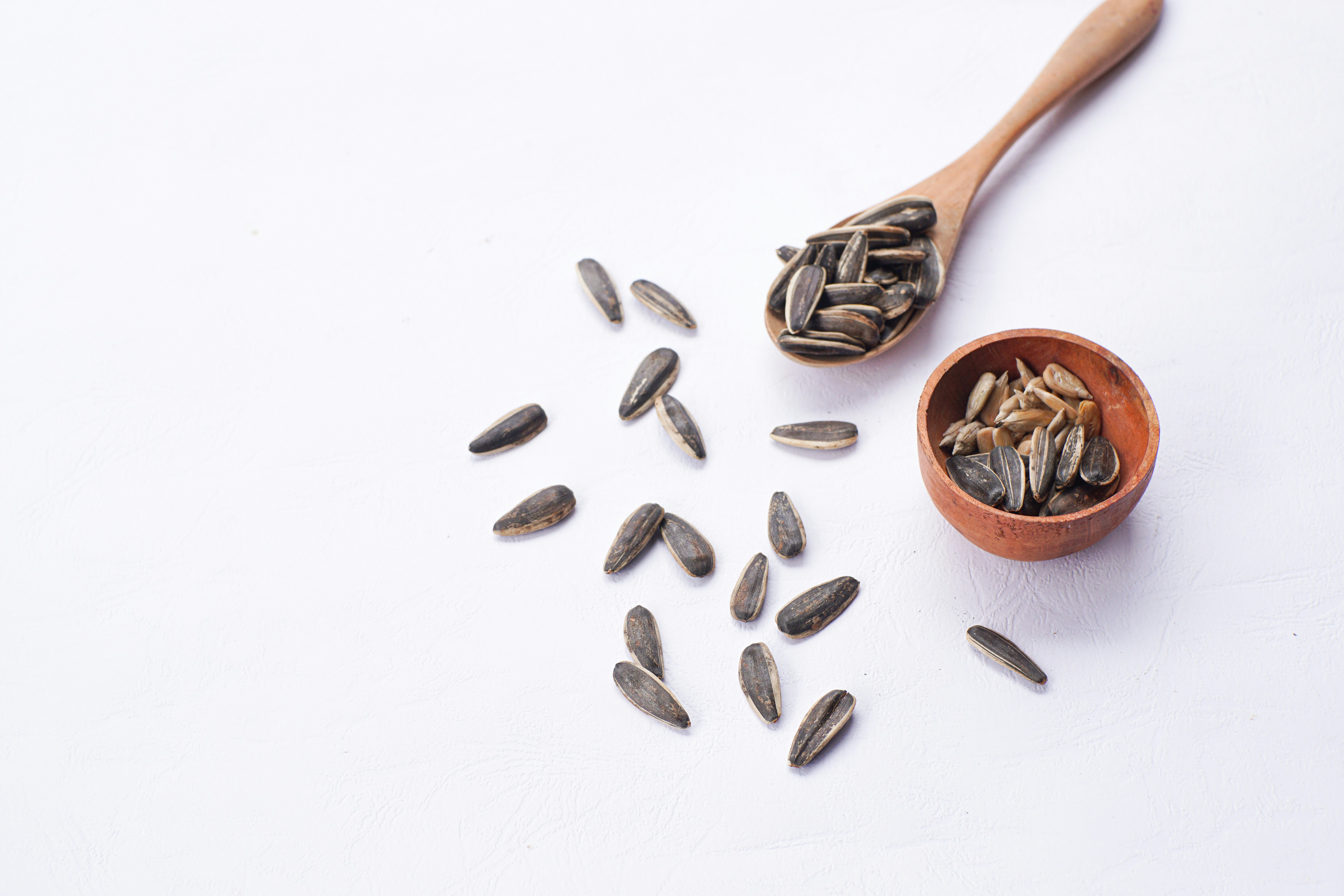 Sunflower seeds are in a bowl and on a spoon.