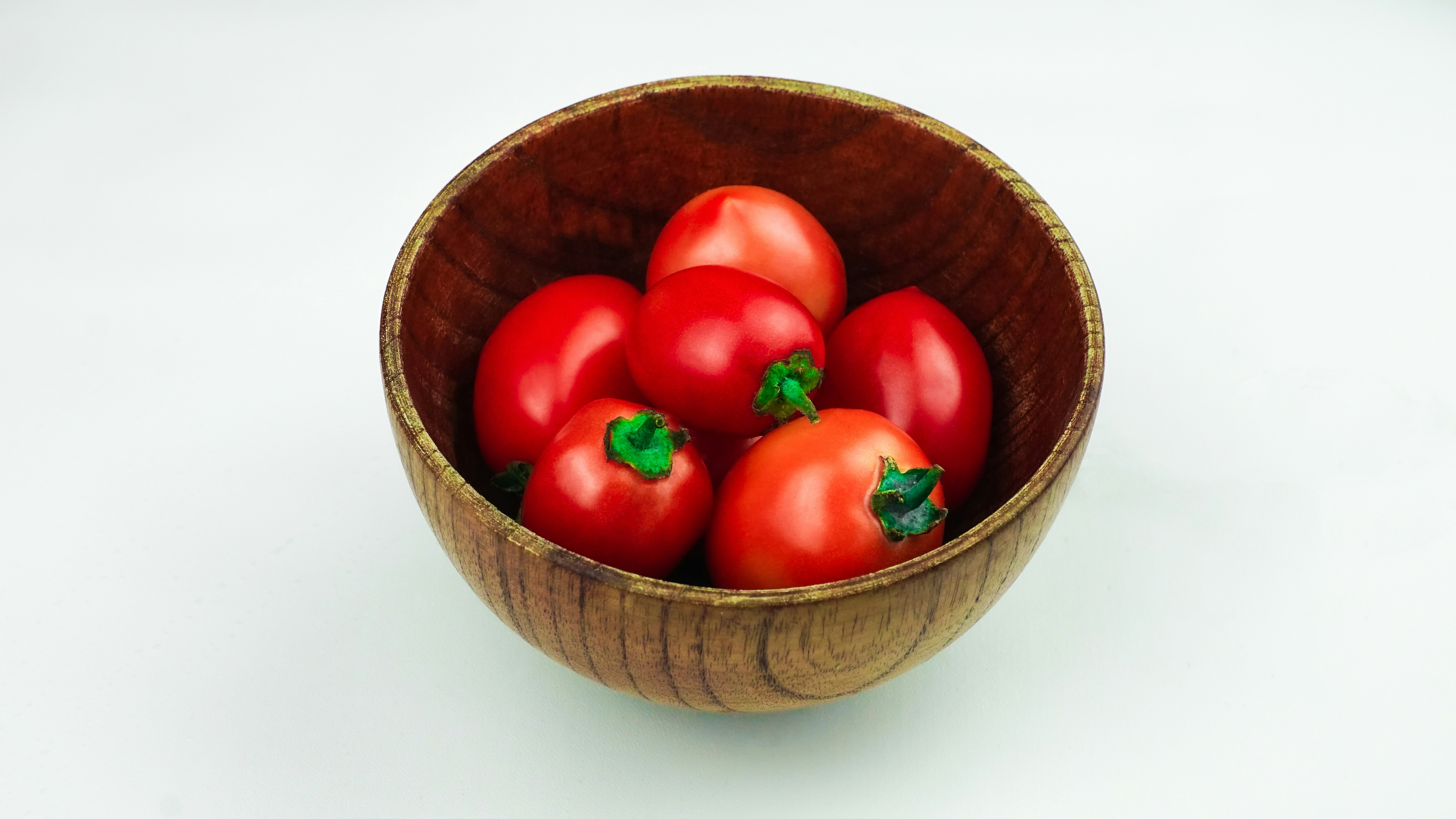 A bowl holds several ripe red tomatoes.