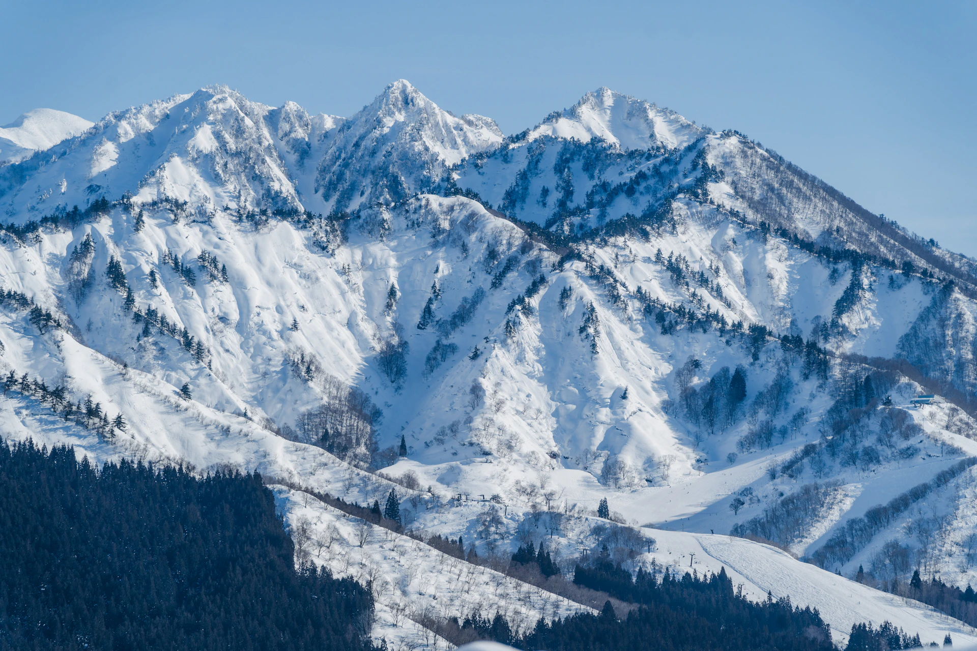 Snow-covered mountain range under a clear, blue sky.
