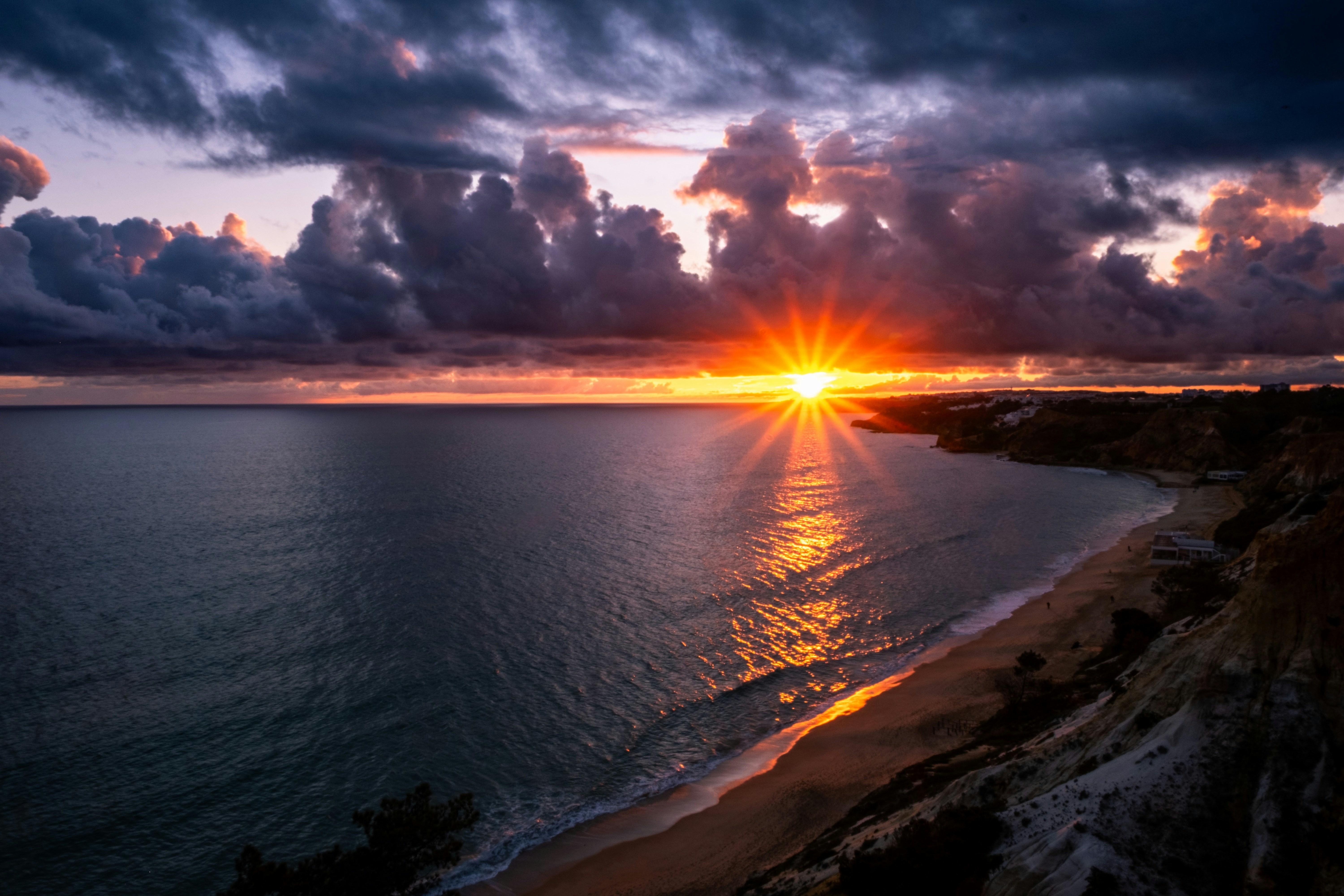 Dramatic sunset over ocean and coastline.