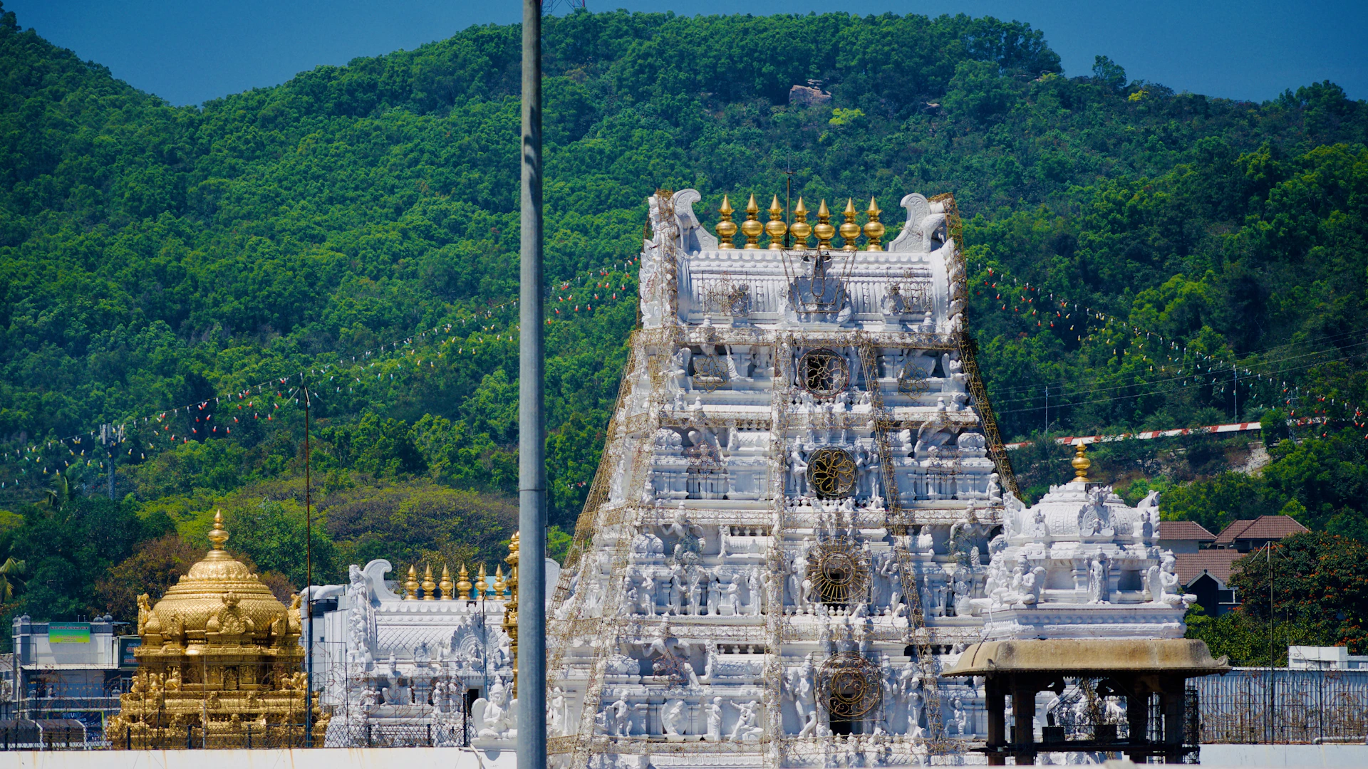 A beautiful hindu temple sits before a lush mountain.