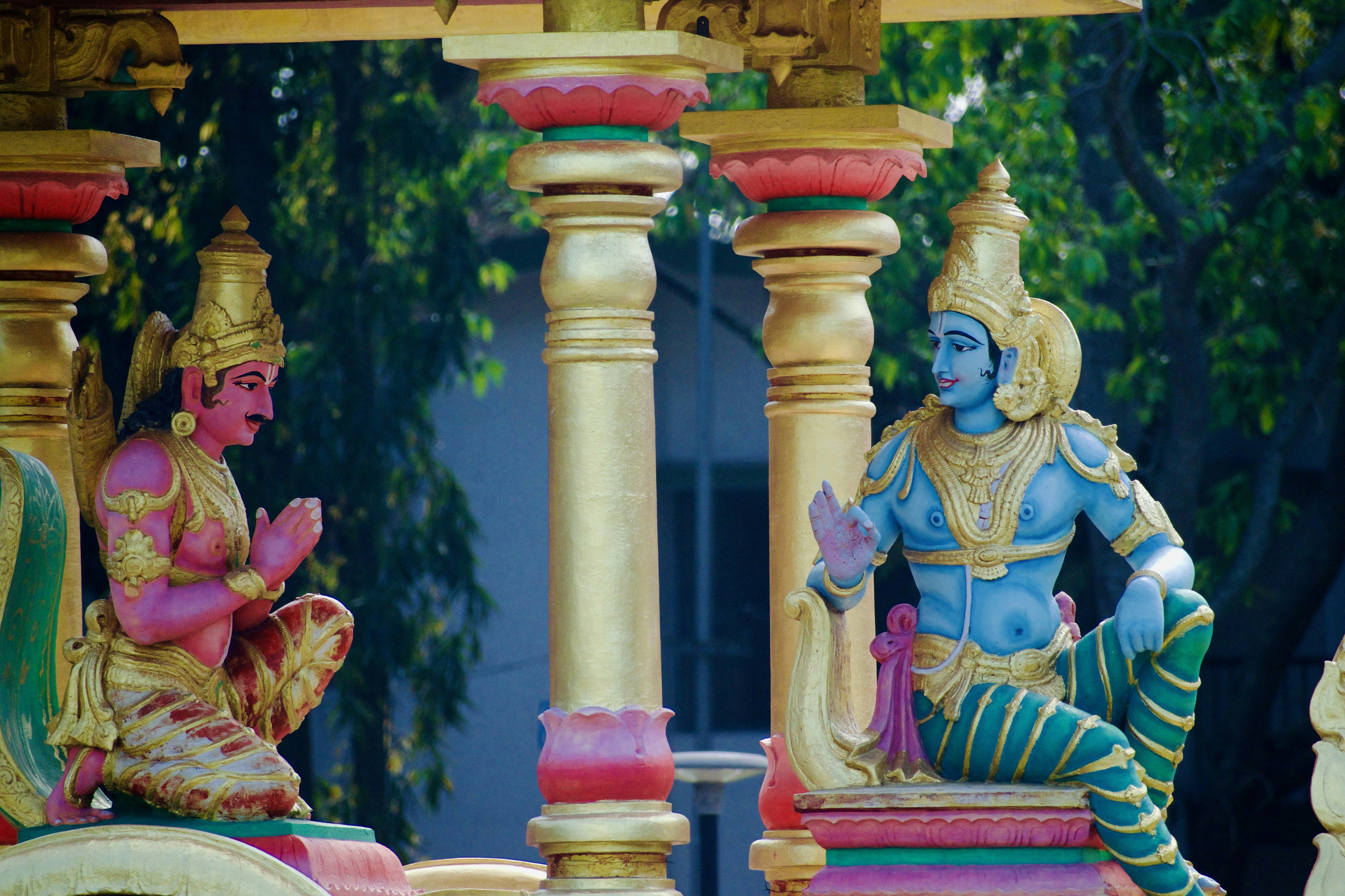 Statues of hindu gods sit in a colorful structure.