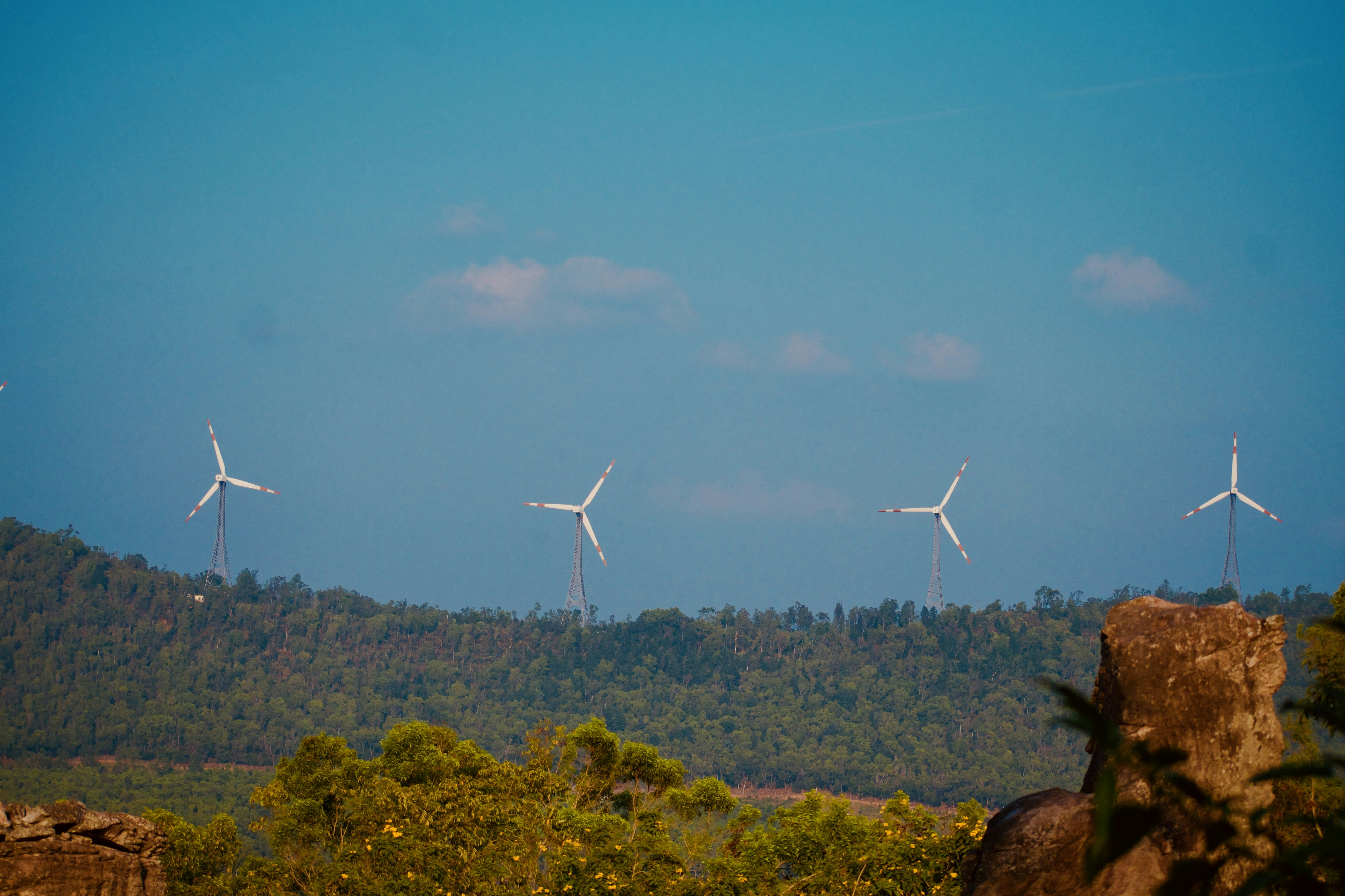 Wind turbines stand tall against the blue sky.