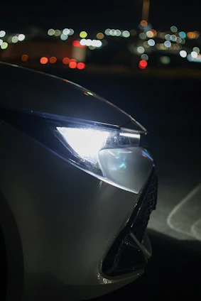 Car headlight glowing brightly at night.