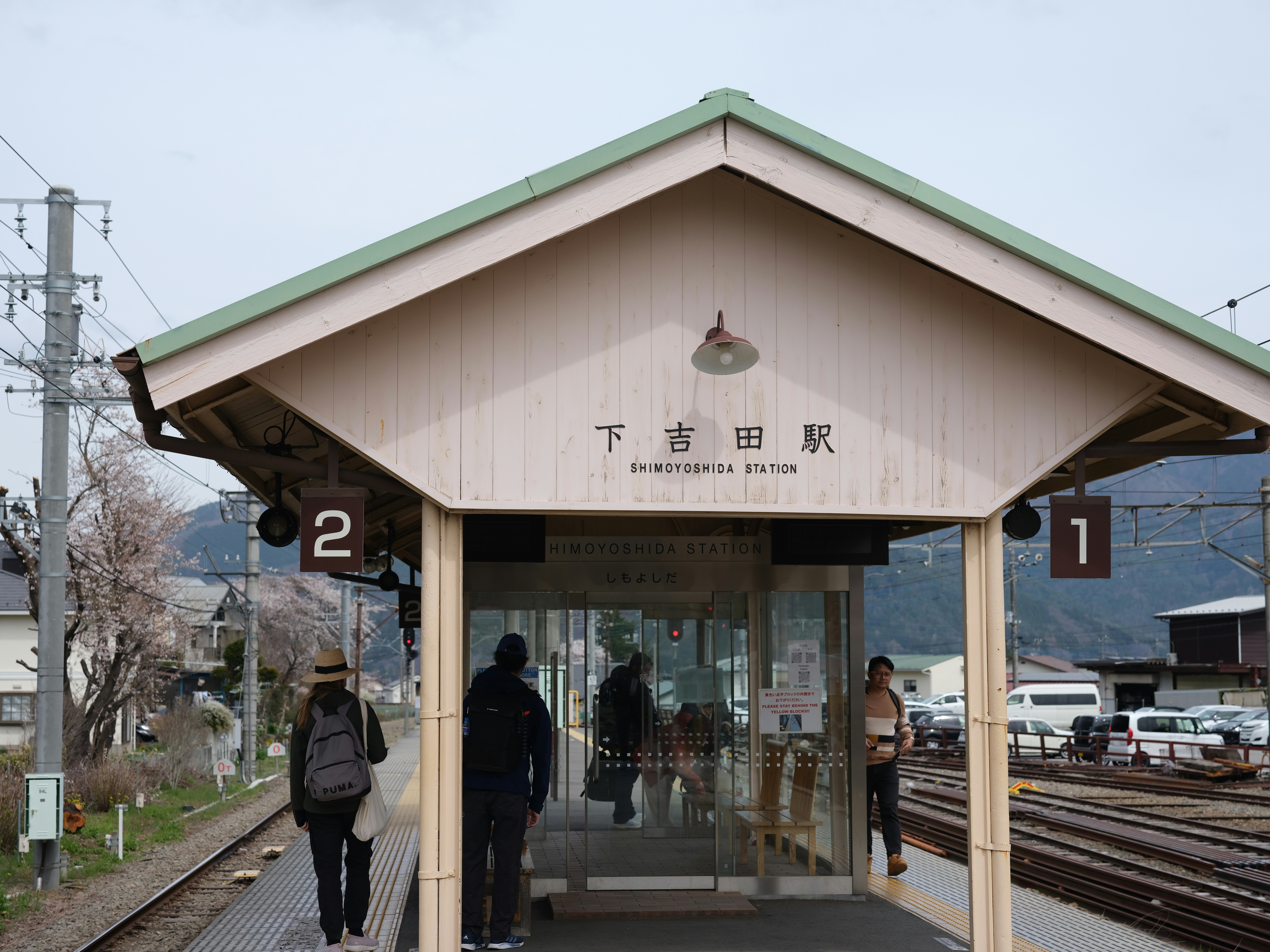 A japanese train station with people waiting.