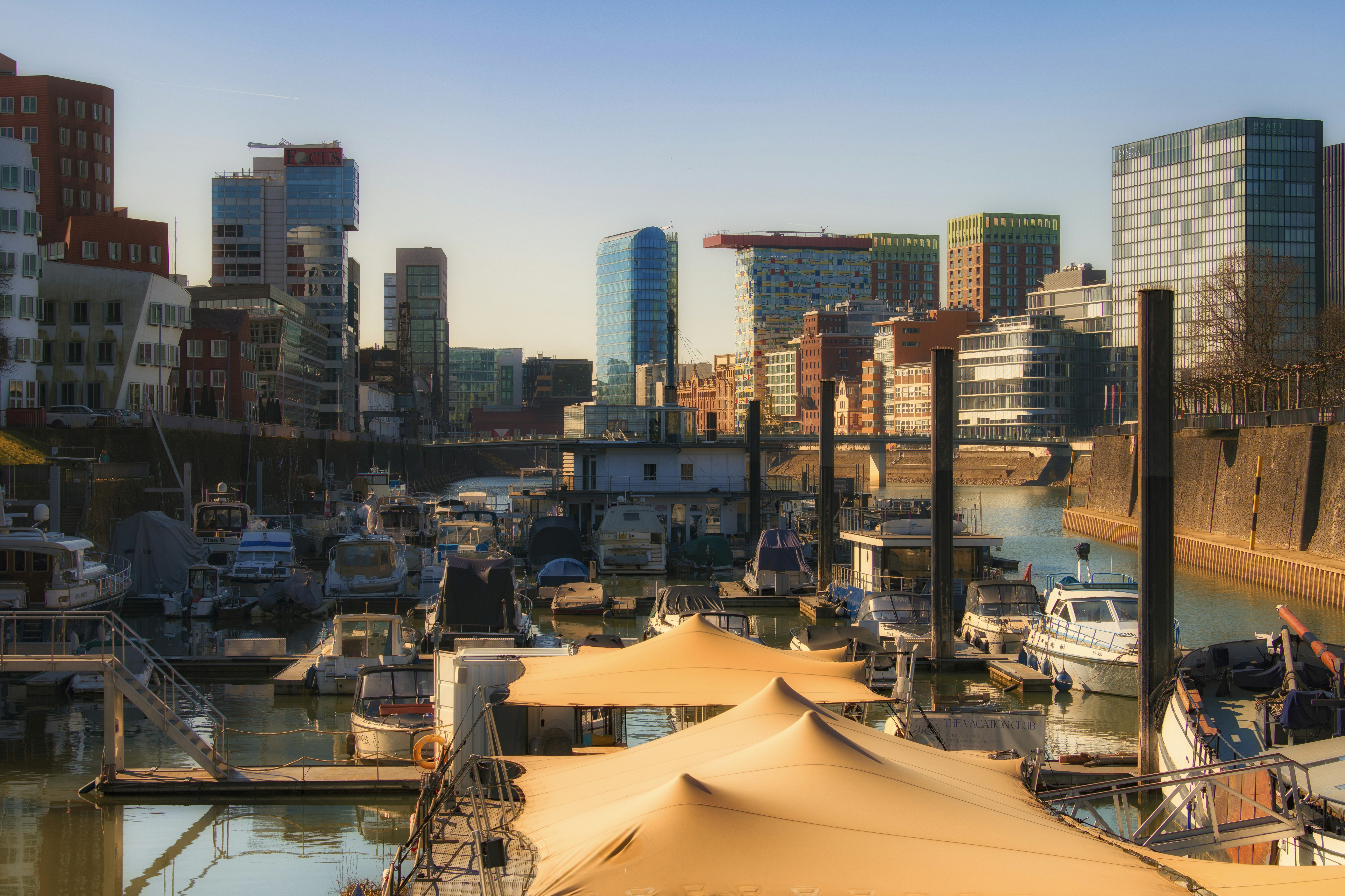 Boats dock in a city harbor with skyscrapers.