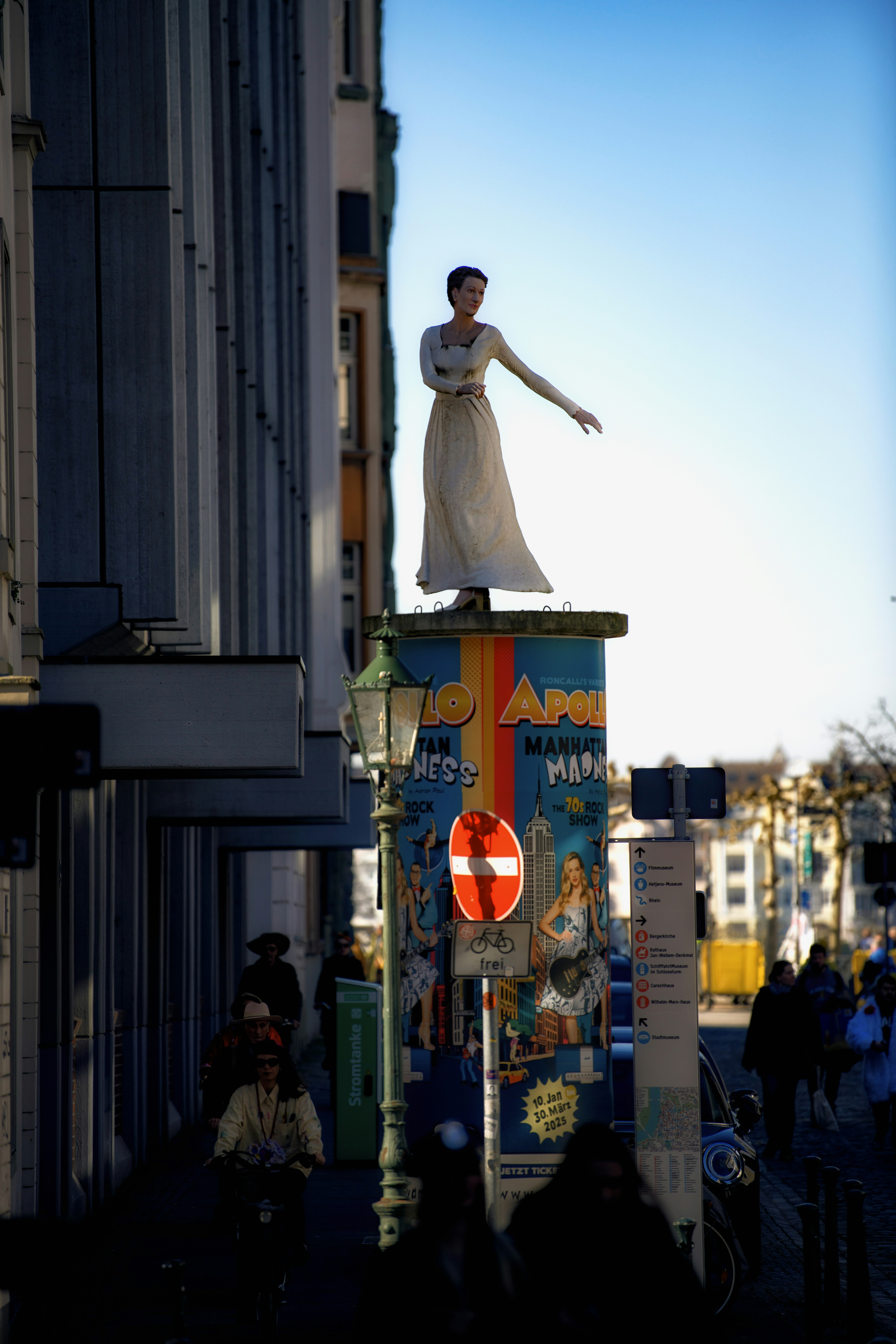 A statue stands on a building in a city.