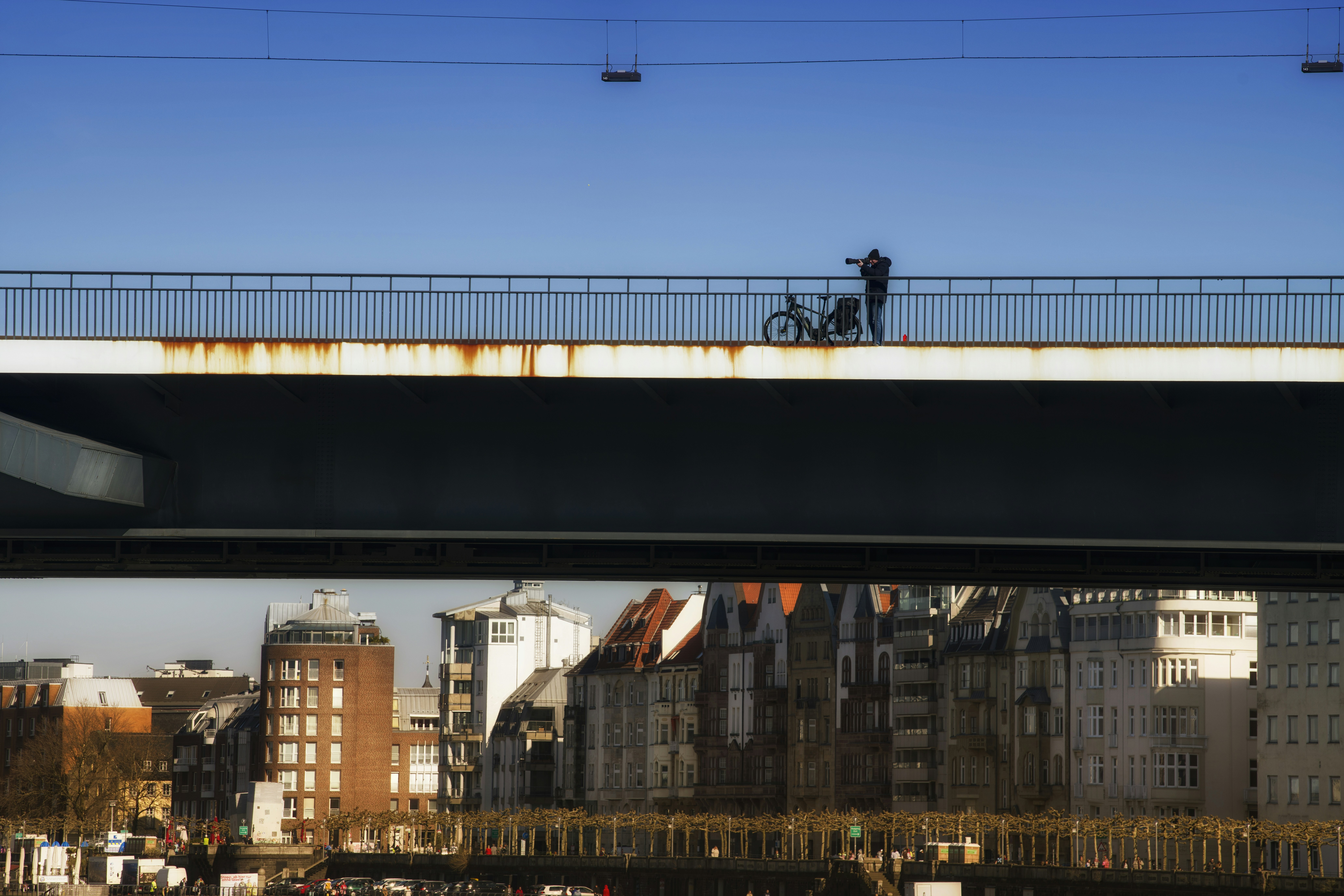 A person stands on a bridge with a bicycle.