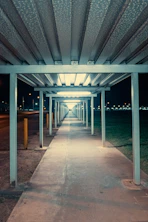 Empty walkway under a long canopy at night.