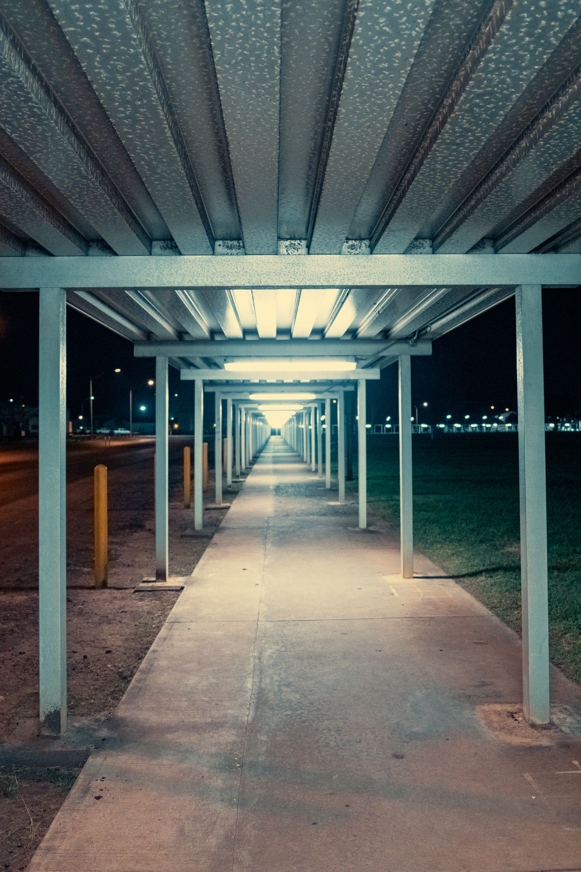 Empty walkway under a long canopy at night.