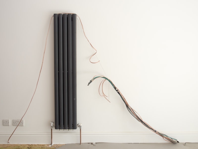 Radiator met leidingen tegen een witte wand