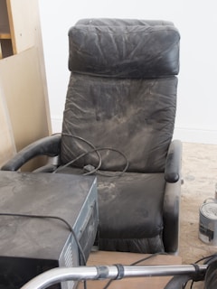 A black recliner chair sitting on top of a hard wood floor