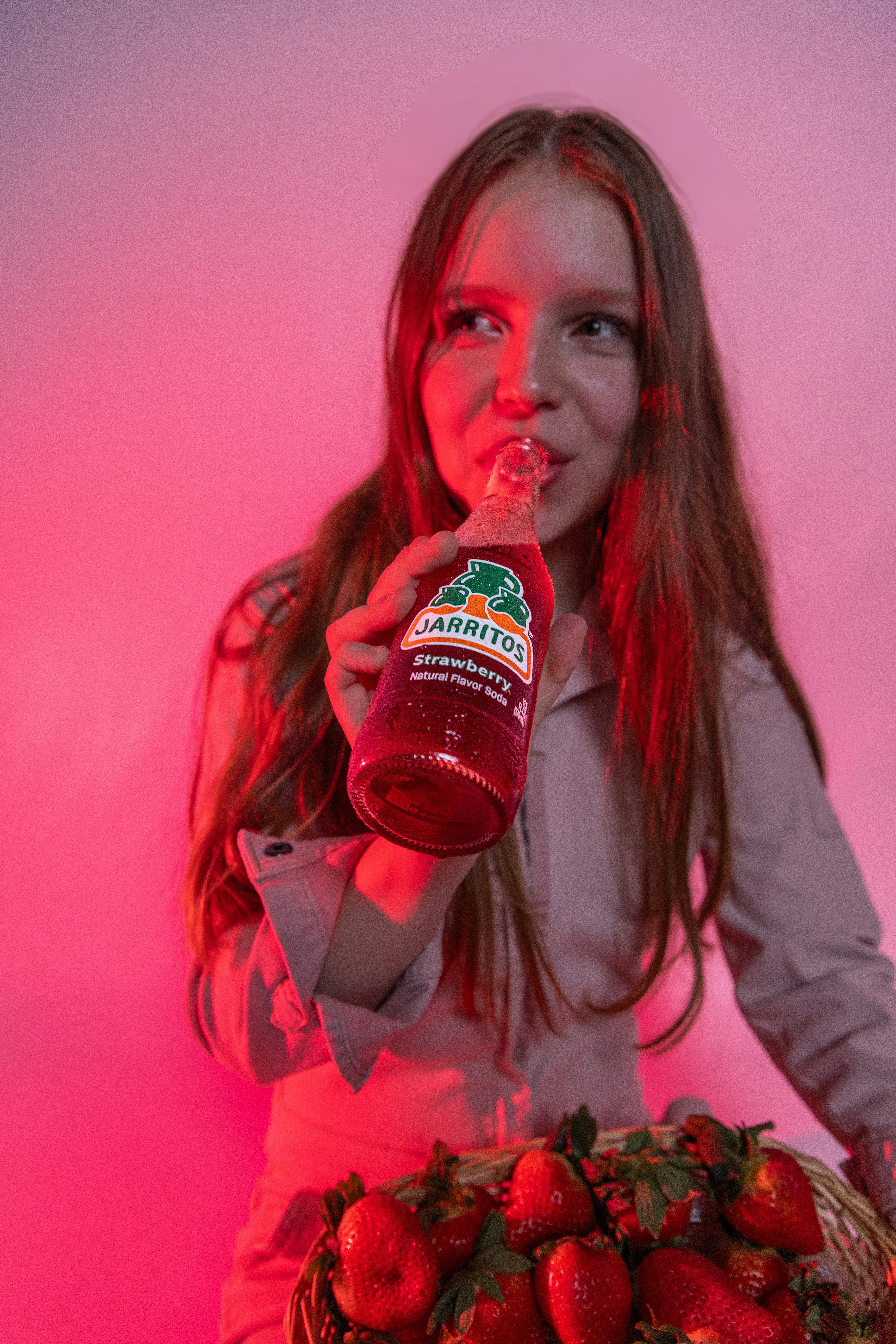 A woman drinks jarritos strawberry soda.