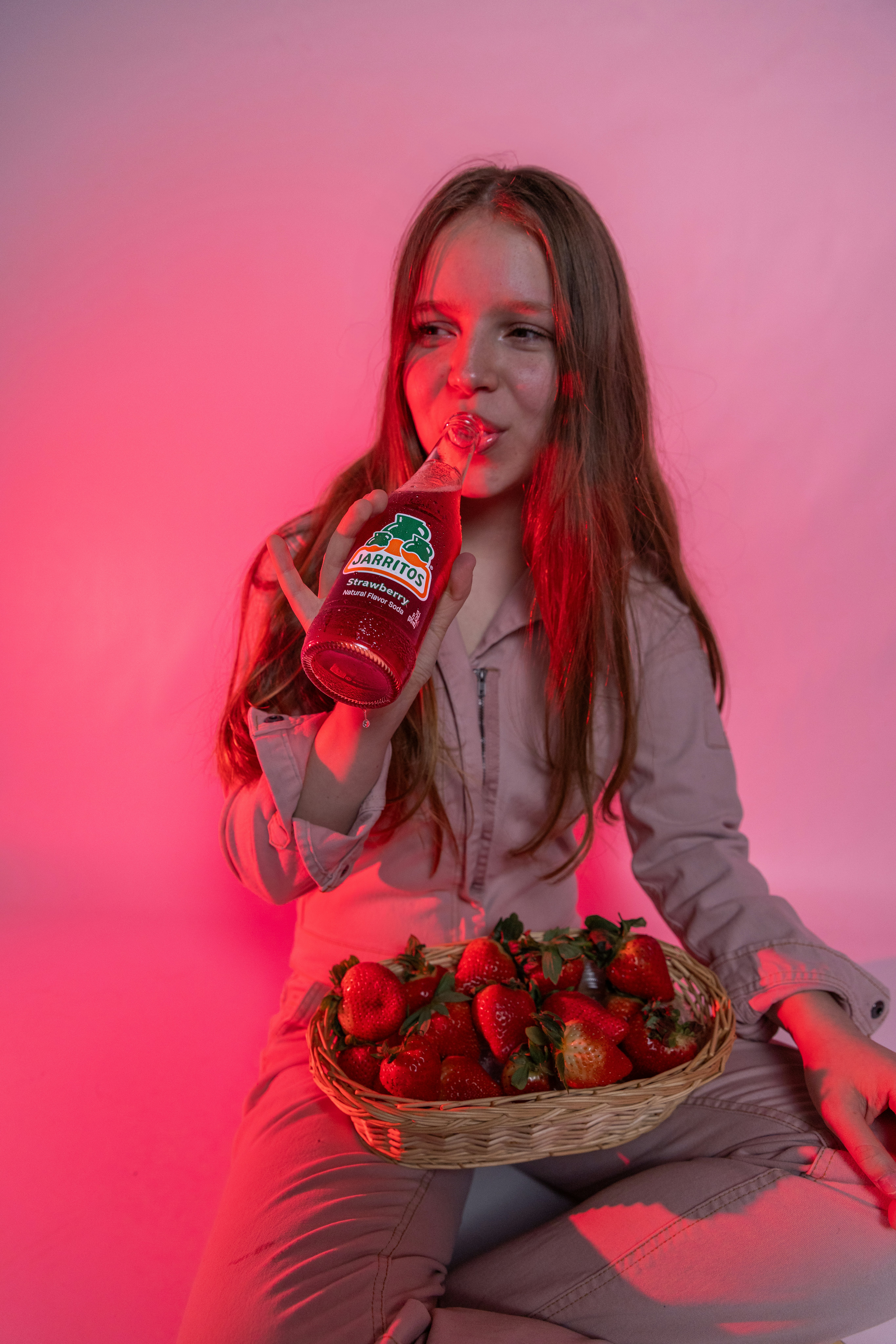 Girl sips strawberry juice with a basket of berries.