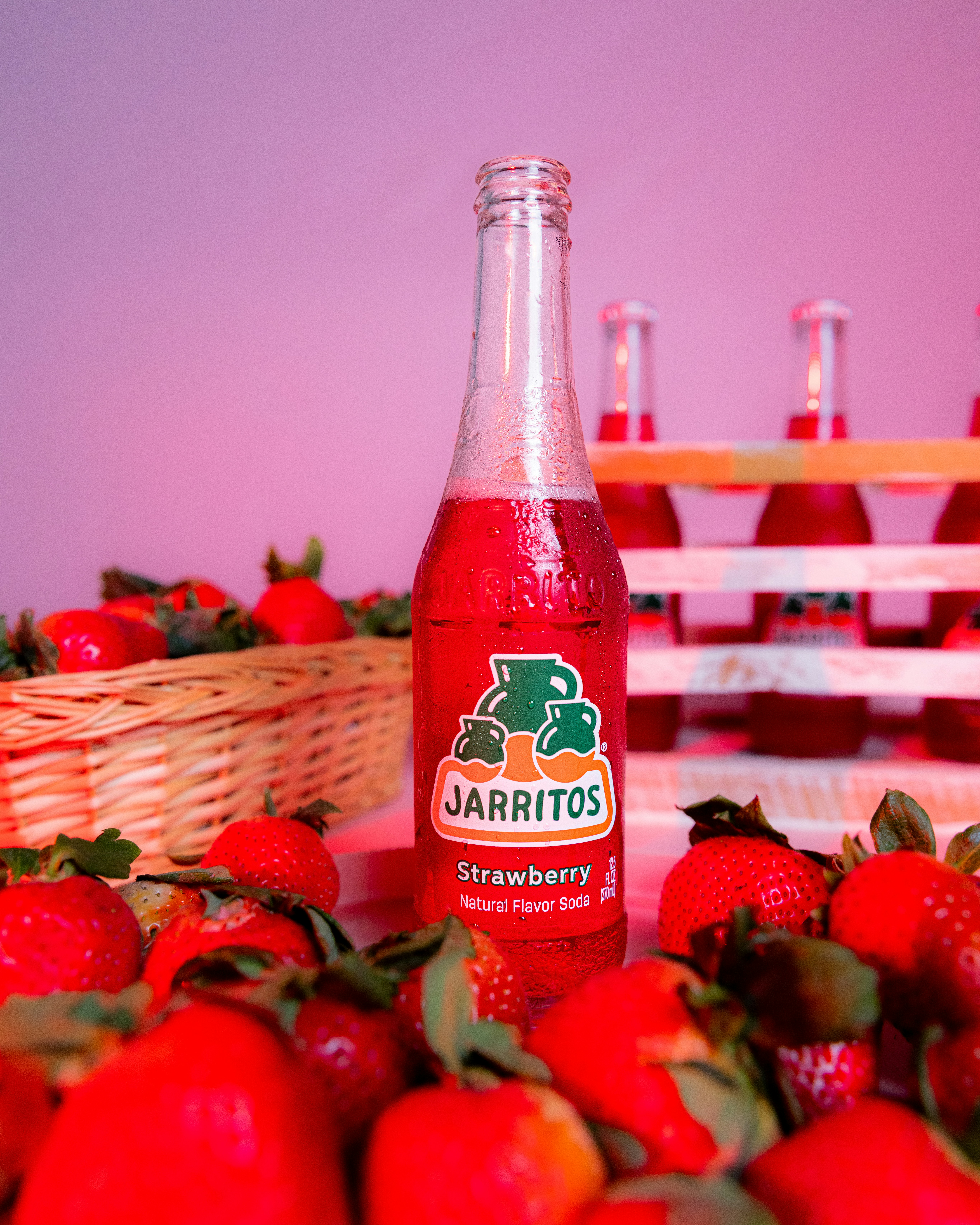 Jarritos strawberry soda is surrounded by strawberries.