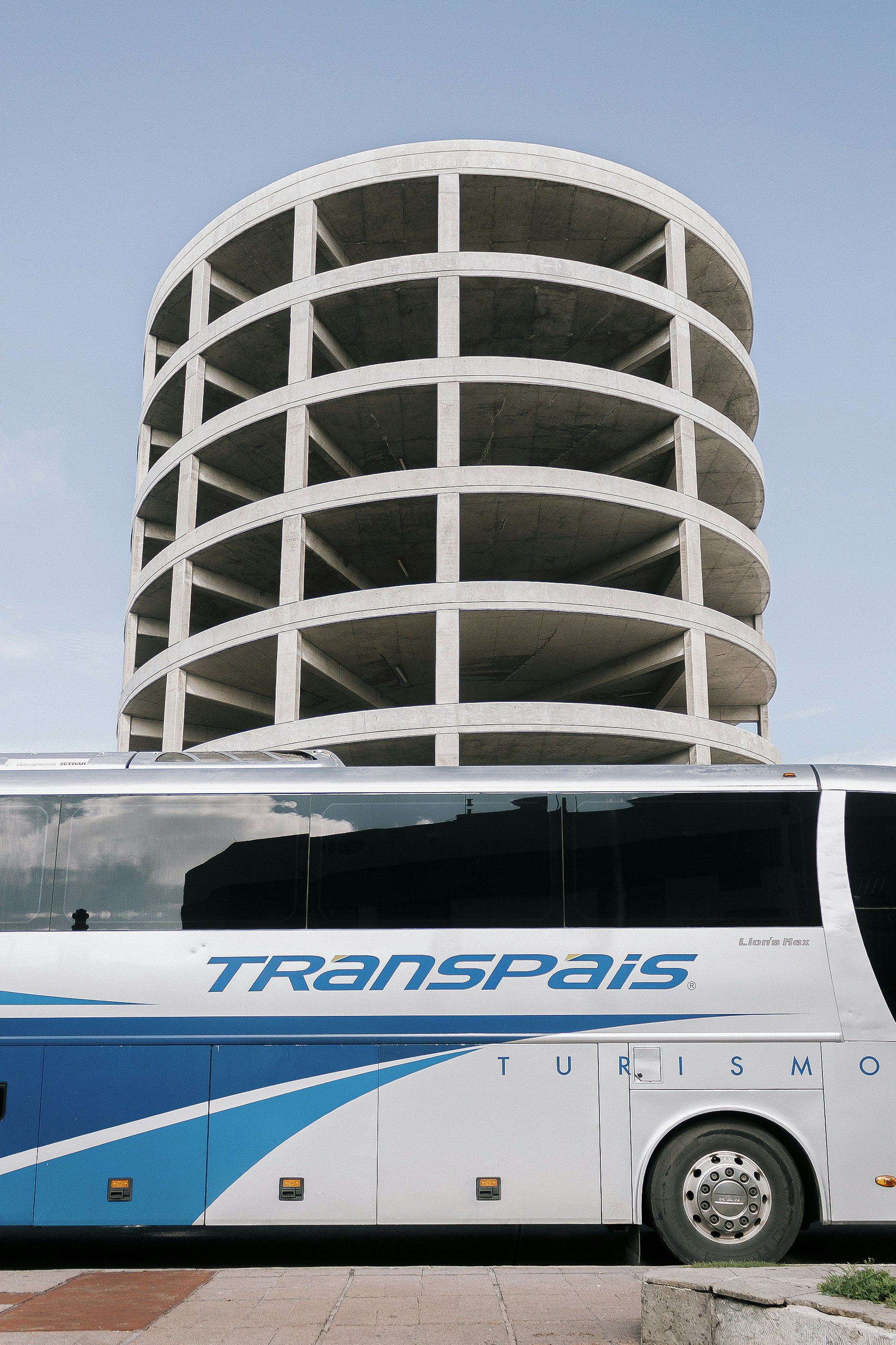 A tour bus is parked near a concrete structure.