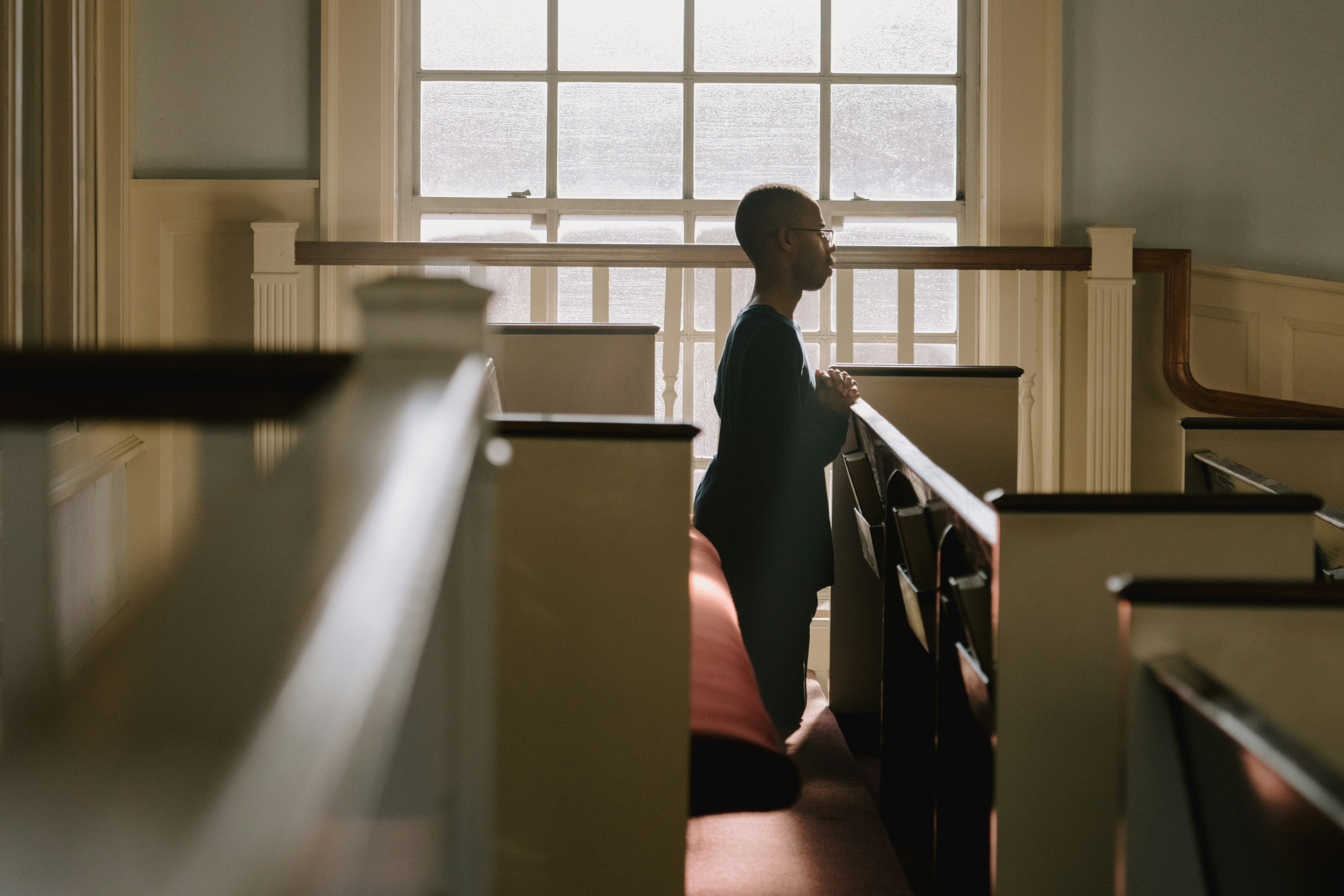 Uma pessoa se ajoelha dentro de uma igreja.