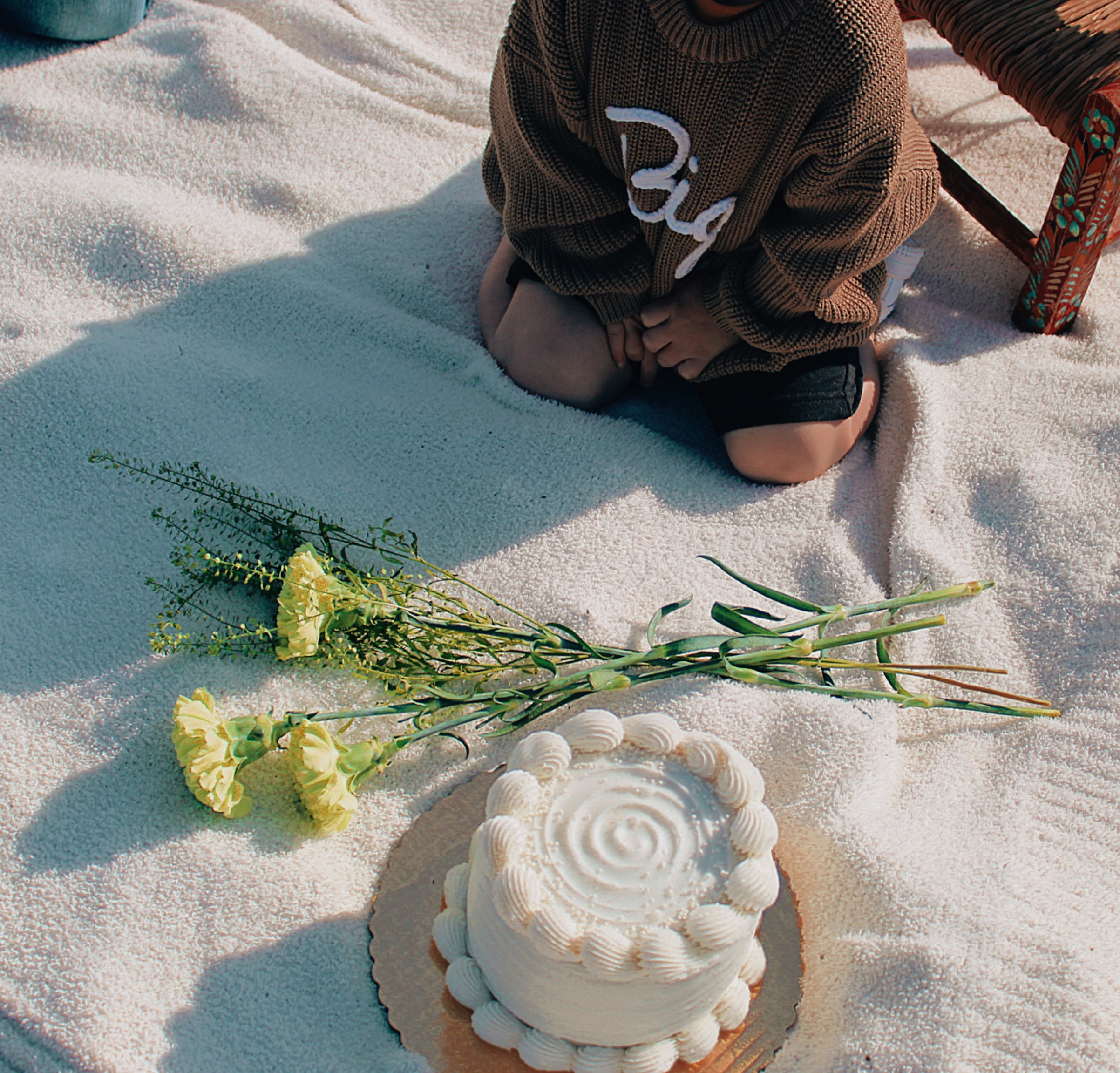 A baby celebrates a birthday with cake and flowers