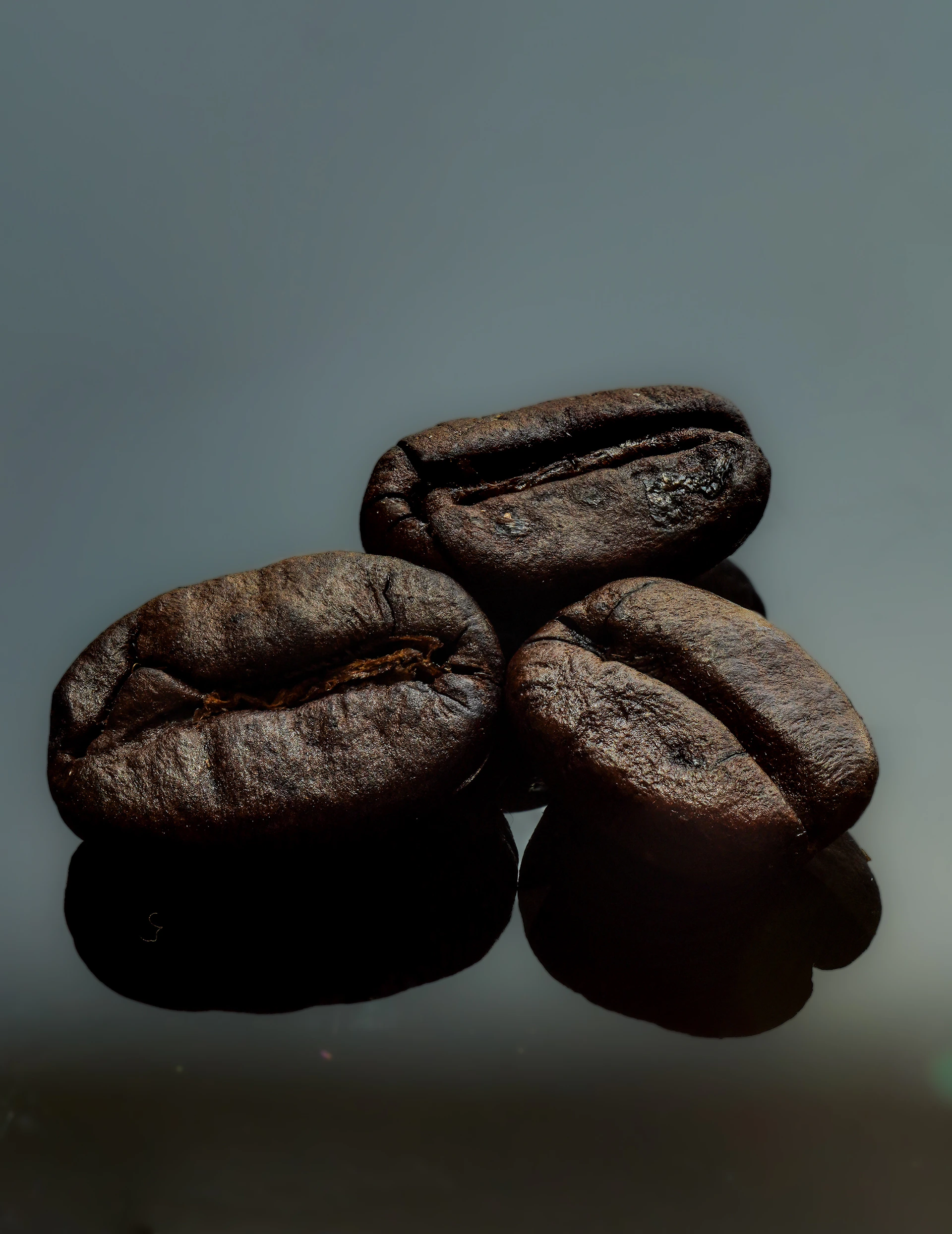 Three roasted coffee beans sit in a pile.