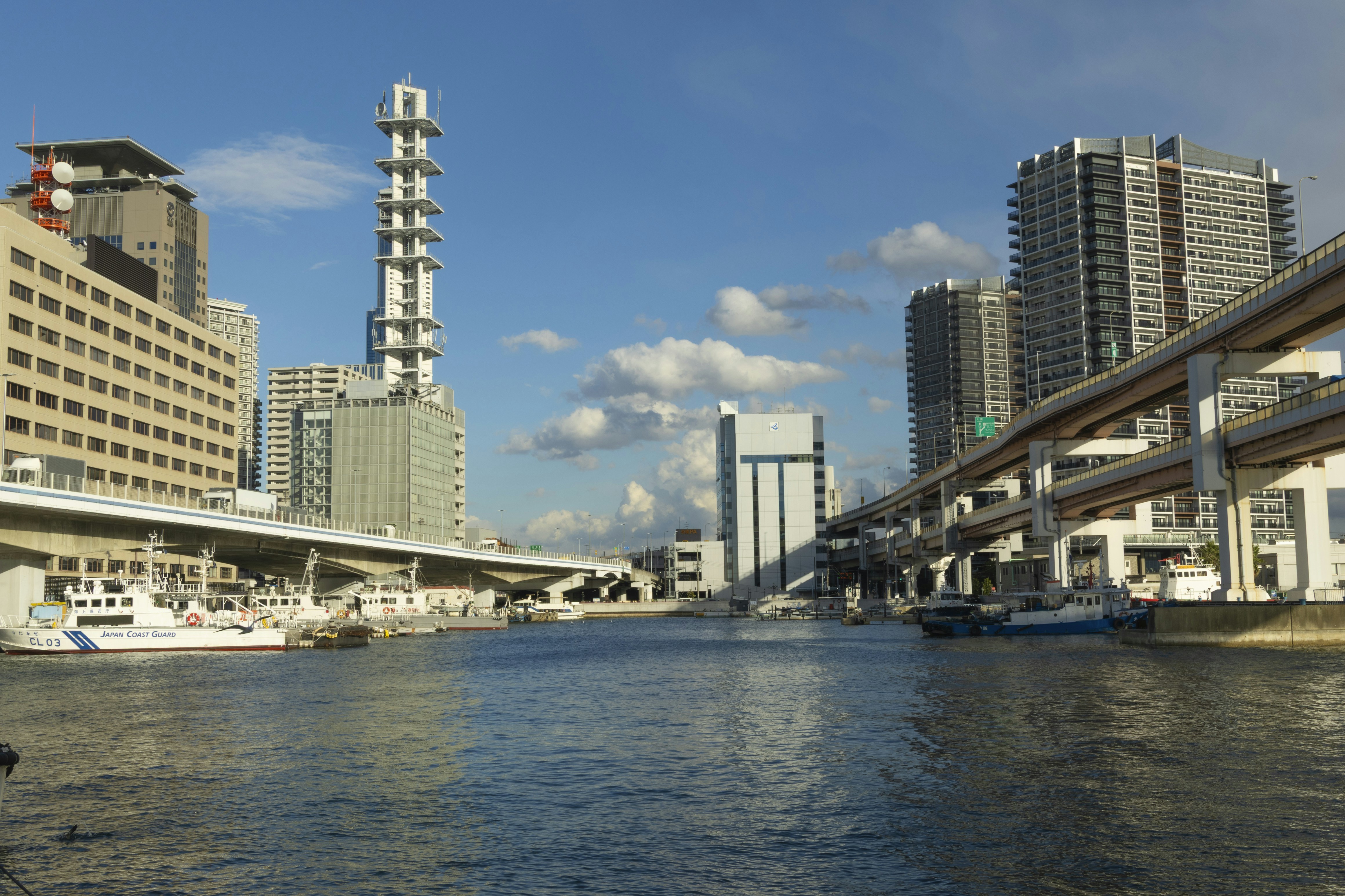 Cityscape with buildings, river, and elevated road.