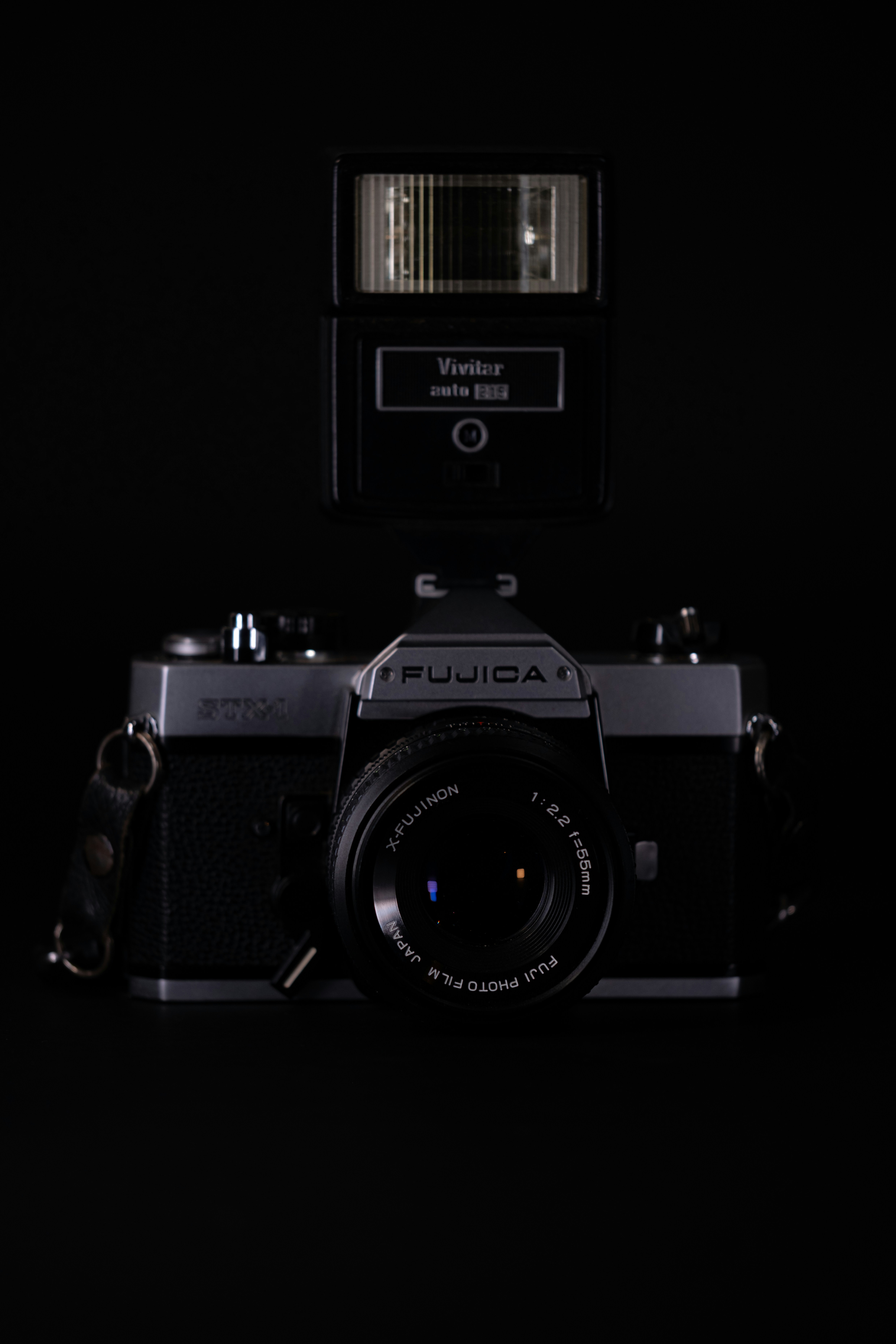 A vintage camera and flash against black.