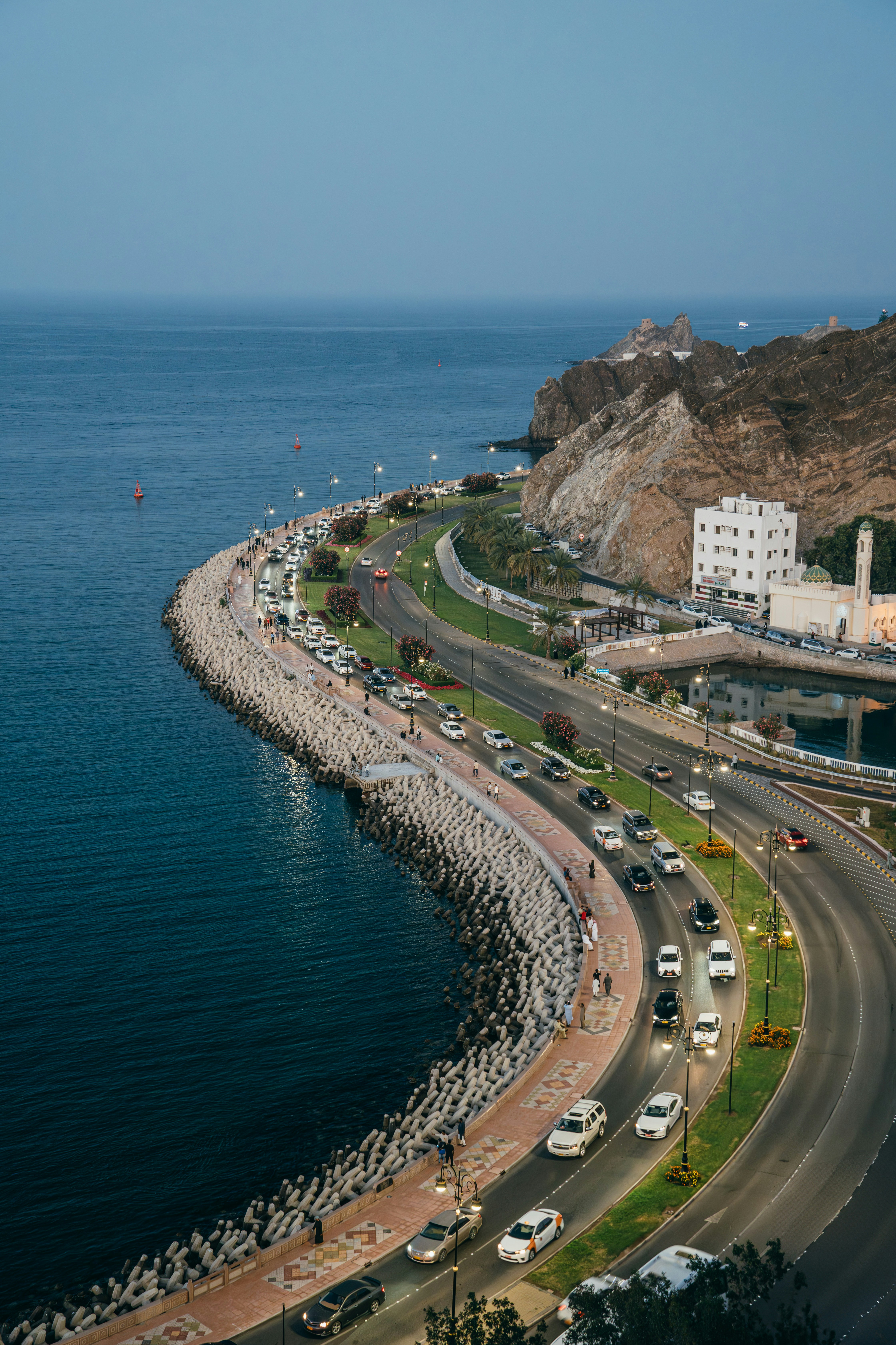 Coastal road with cars near the ocean at dusk.