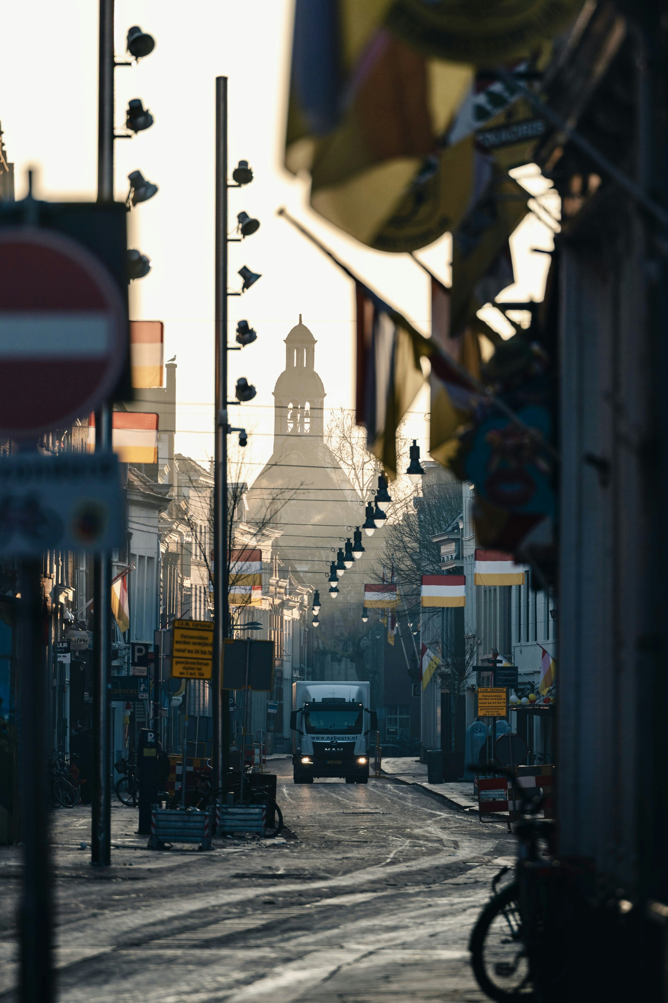 A street with flags and a church in the background.