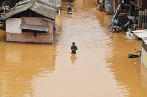 Flooding engulfs homes and a person stands in the water.