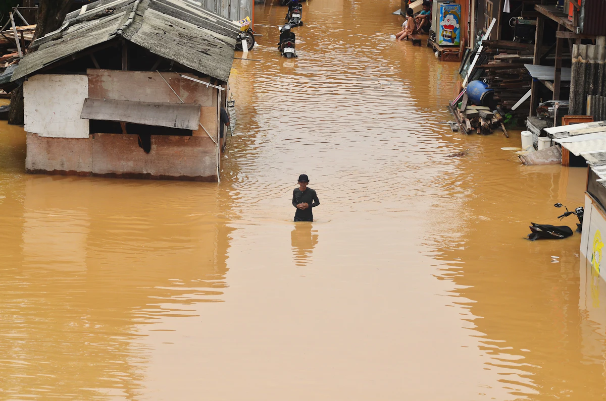 Banjir merendam permukiman dan seseorang berdiri di dalam air